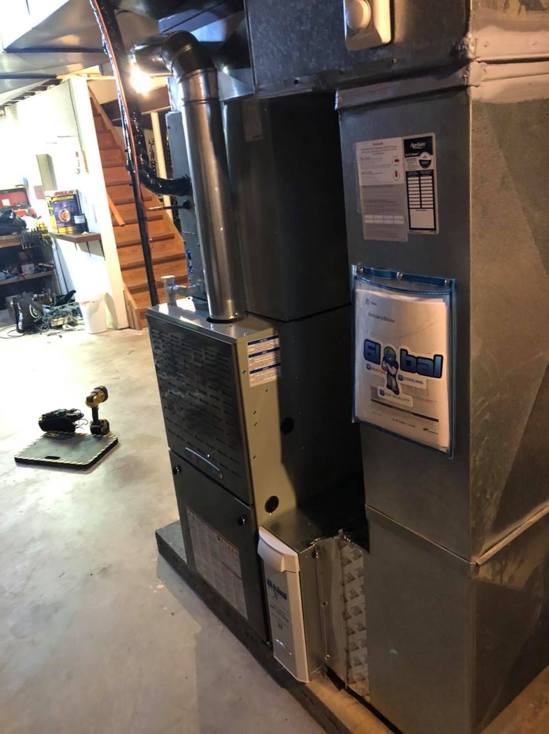 Furnace in a basement. Ductwork and flue pipe visible. Blue and gray tones.
