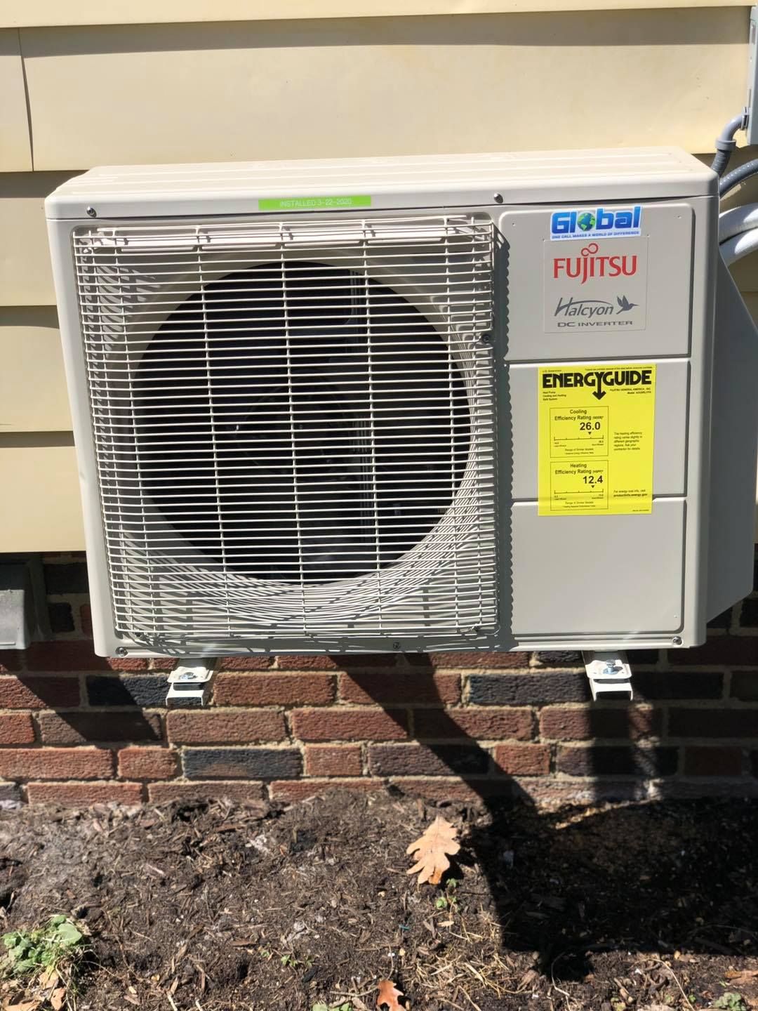 Fujitsu air conditioning unit mounted on brick and siding exterior wall.