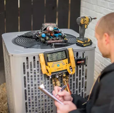 HVAC technician checking AC unit, using gauges and writing on a notepad outdoors.
