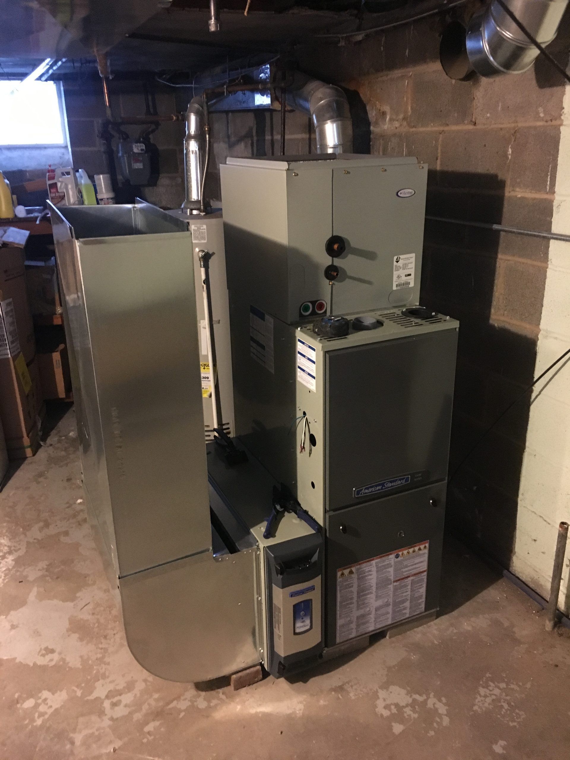 A large, gray heating system unit in a basement setting.