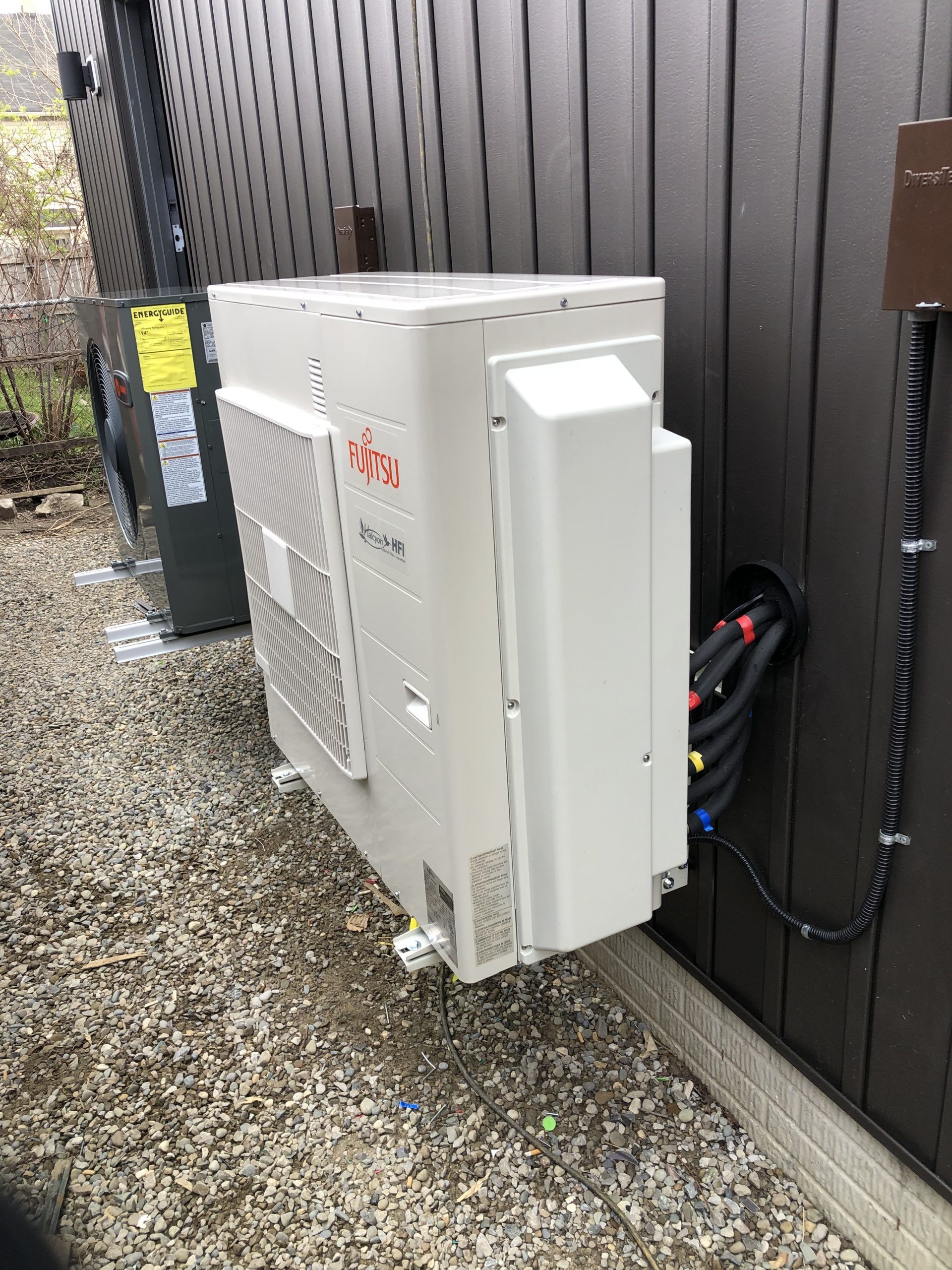 White air conditioning unit mounted on a brown wall, wires run through the wall.