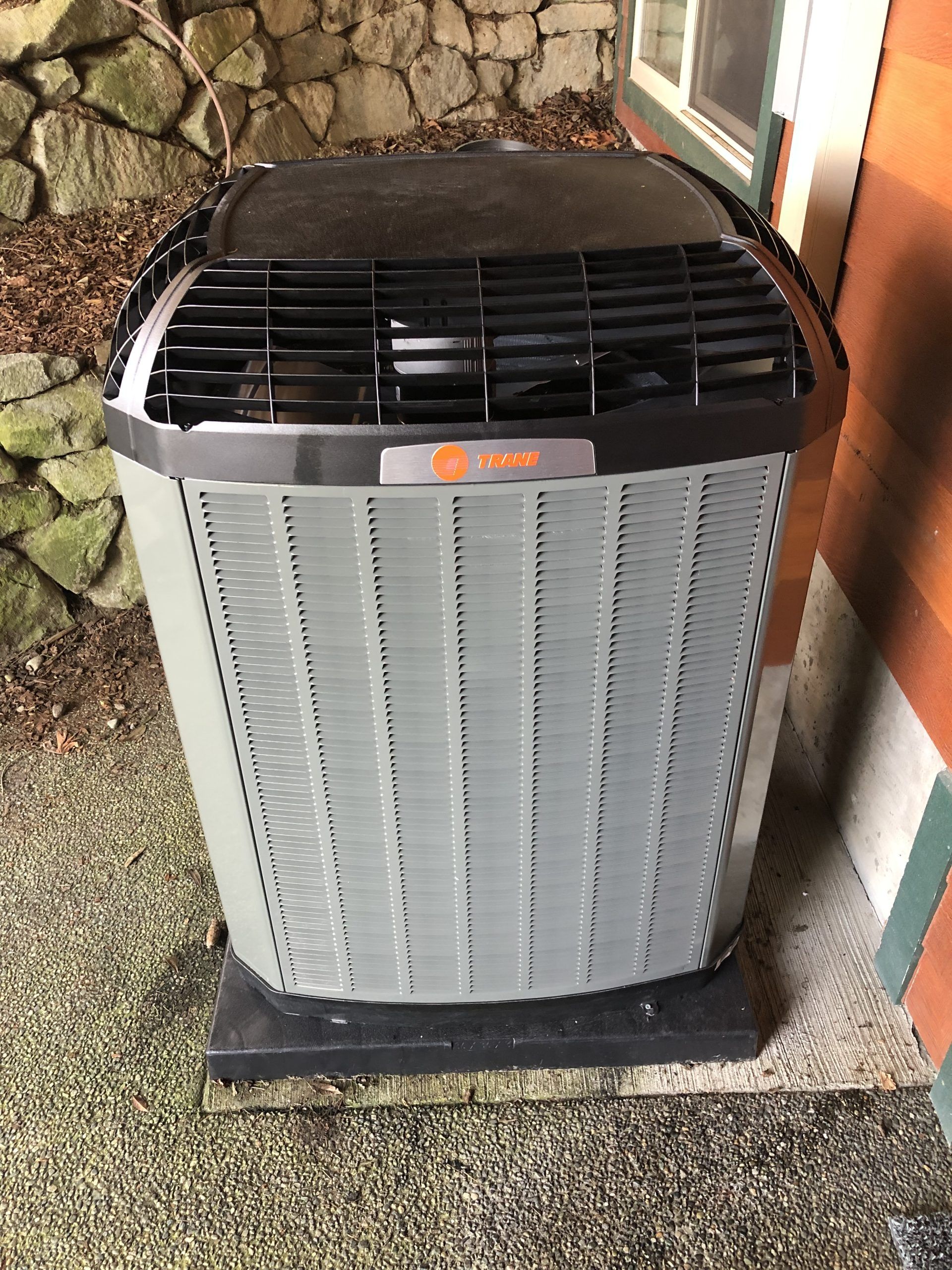 Gray Trane air conditioner unit outdoors next to a building.