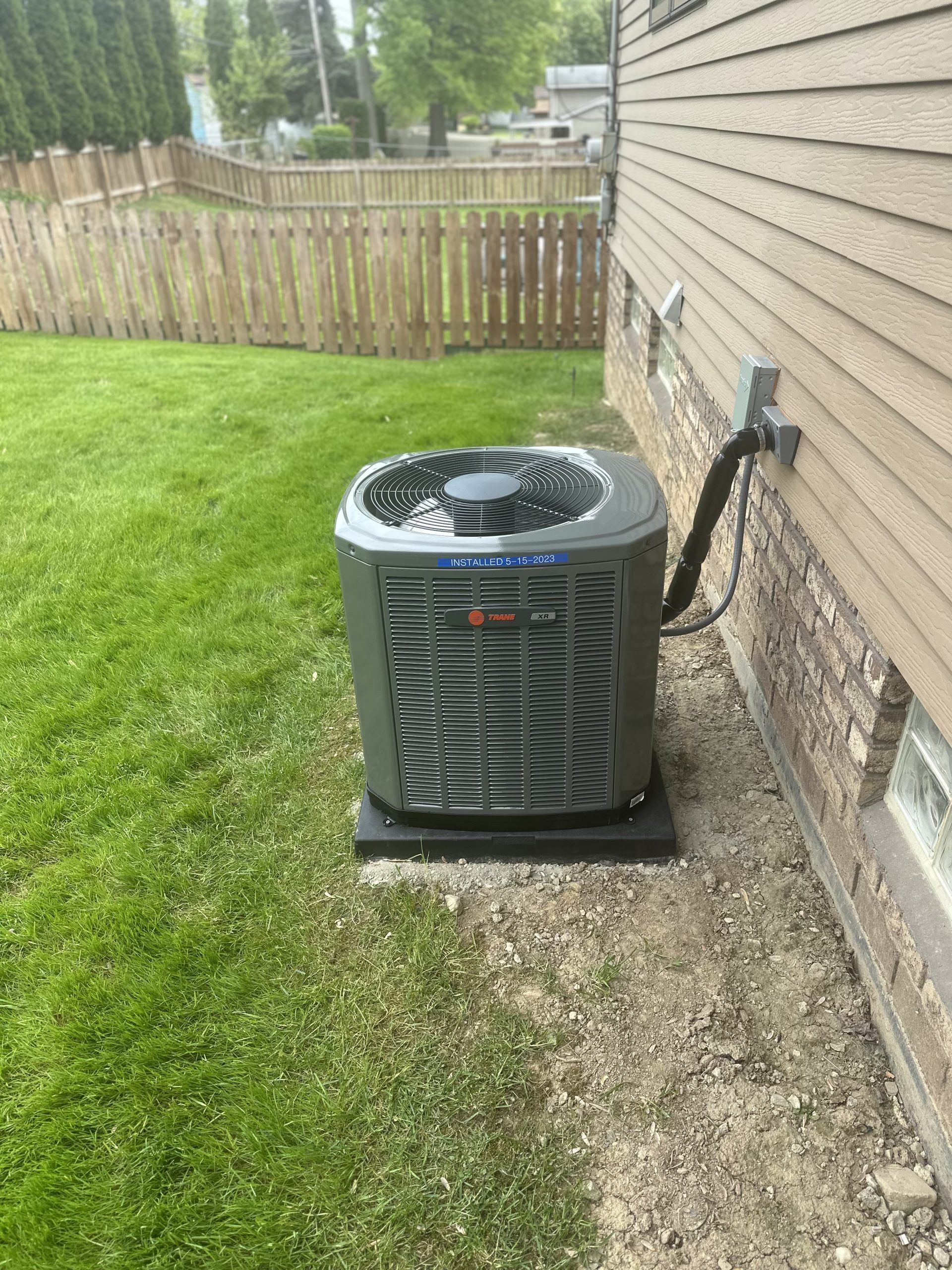AC unit next to a house on a grassy lawn.