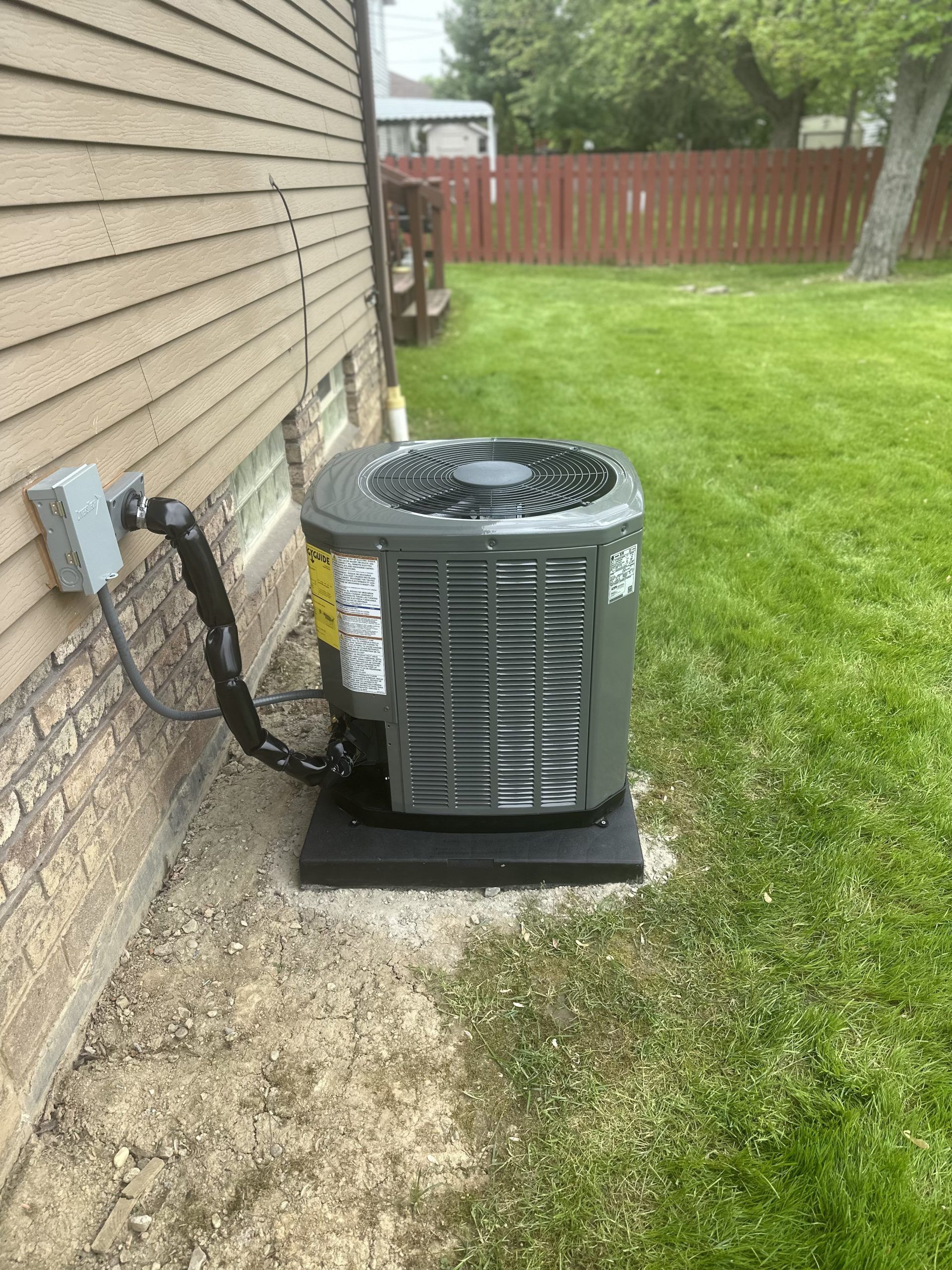 An air conditioning unit next to a house on a grassy lawn.