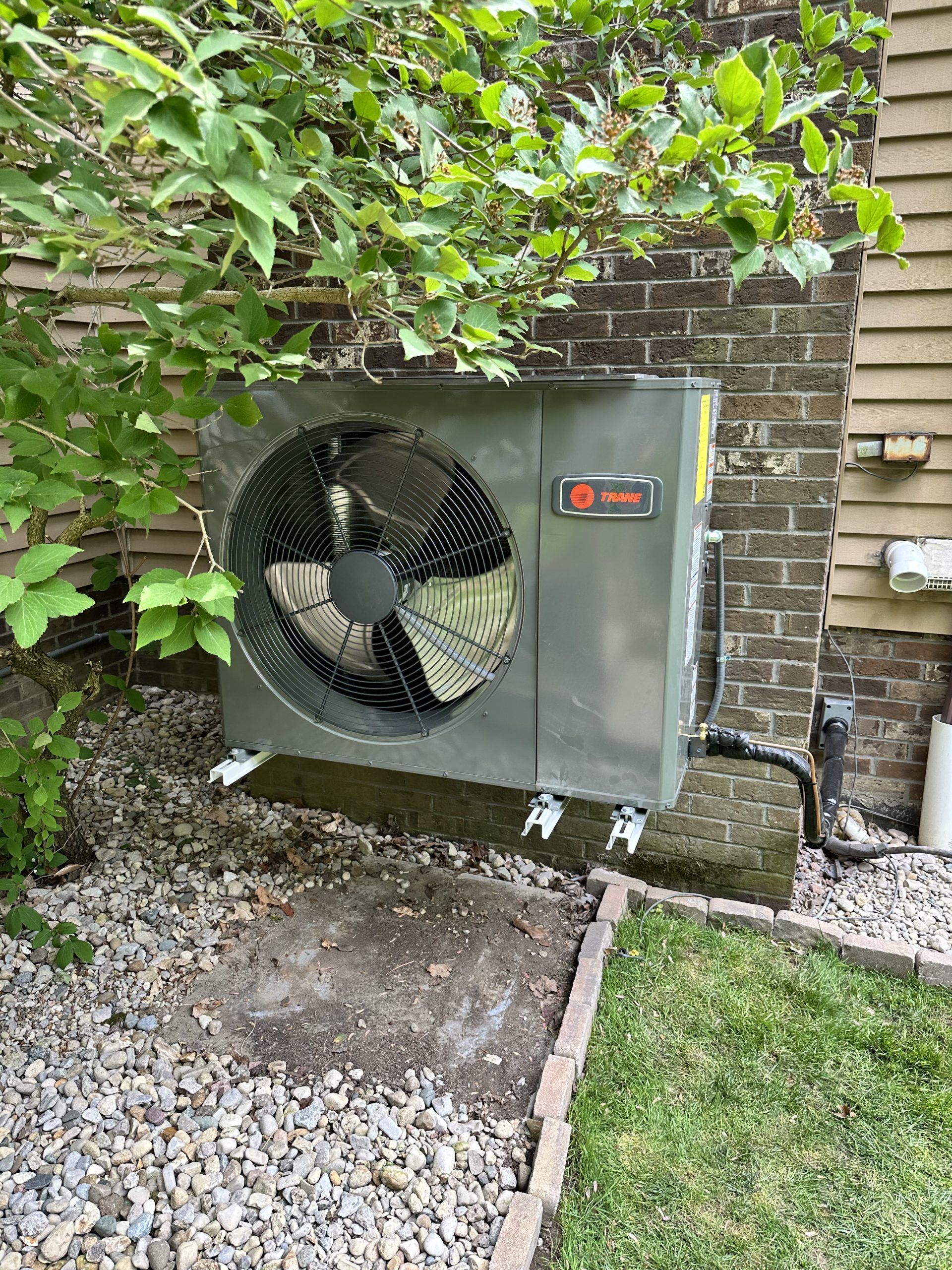 Gray Trane air conditioner unit mounted on a brick wall