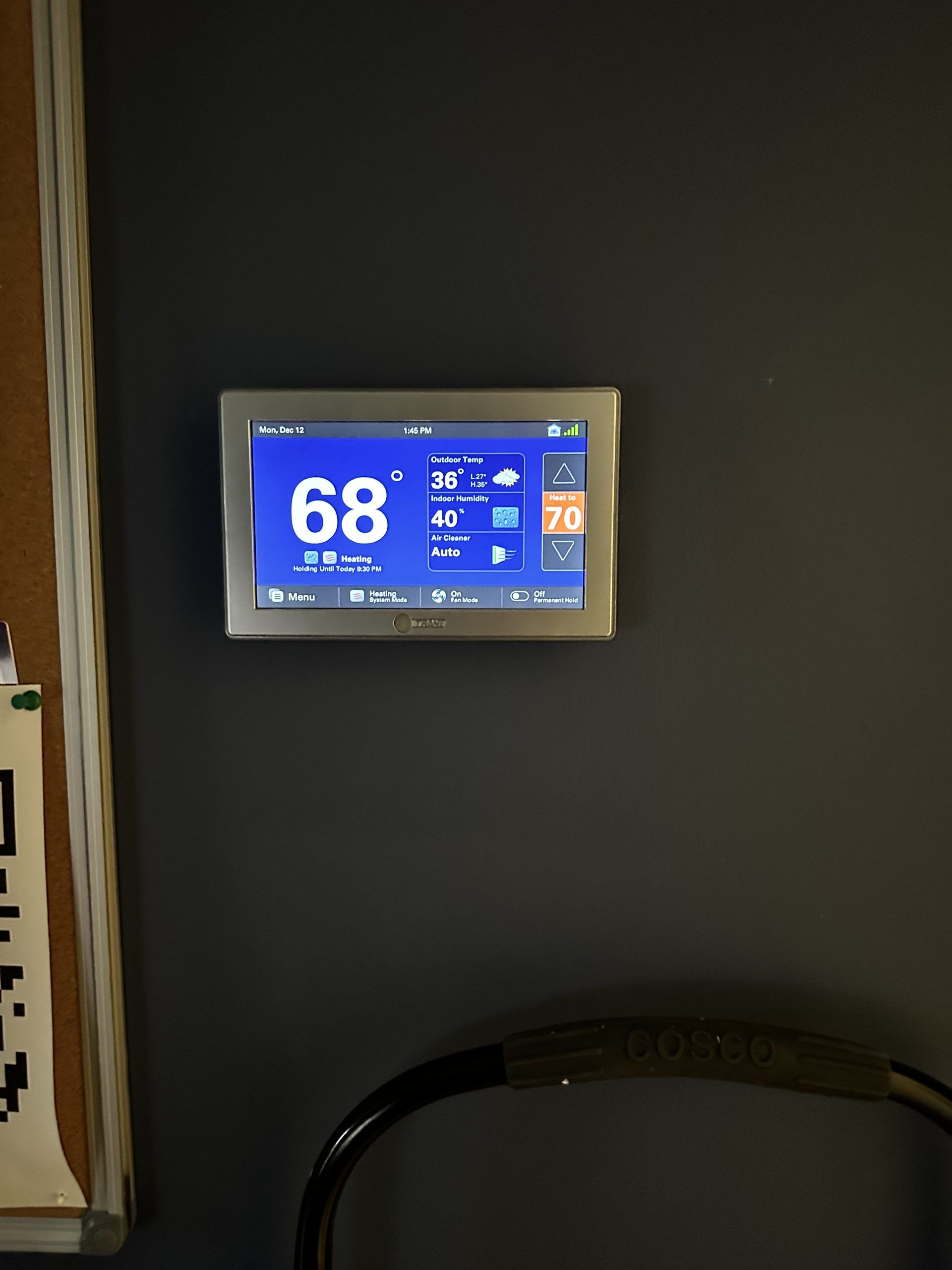 Thermostat on a gray wall displaying a temperature of 68 degrees.