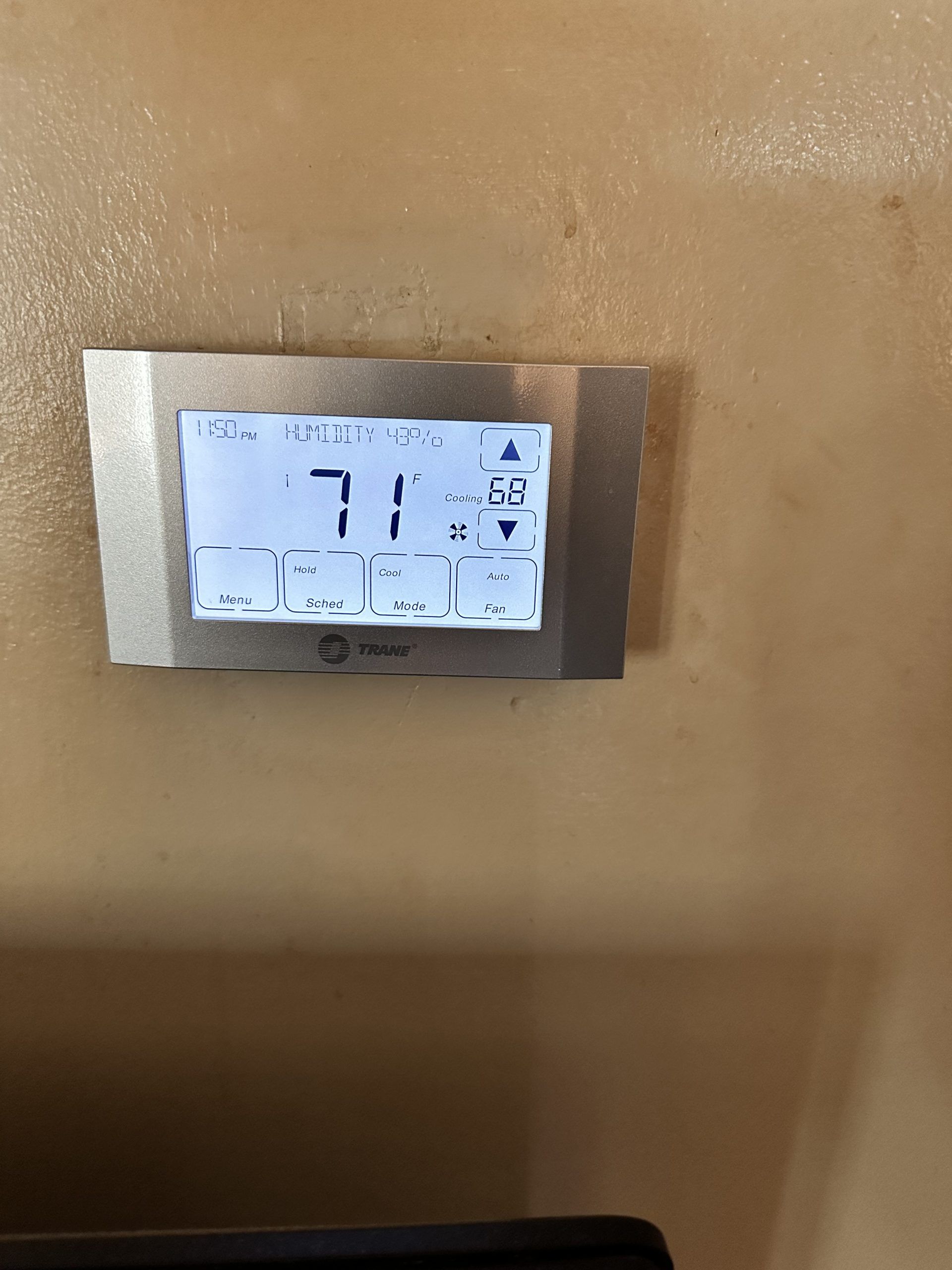 Digital thermostat on a wall, displaying a temperature of 71 degrees.