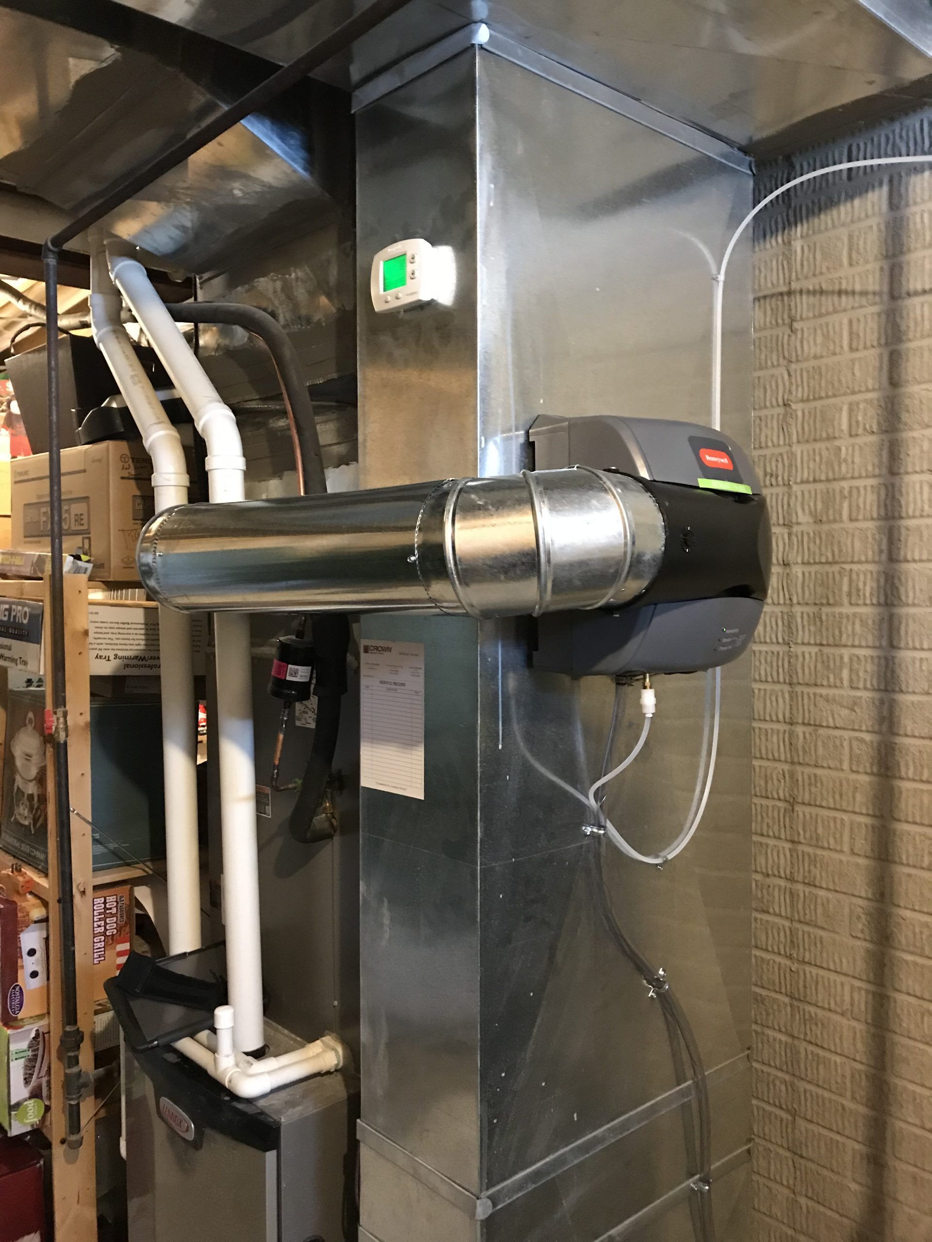 A furnace system in a basement with silver ductwork and humidifier attachment.