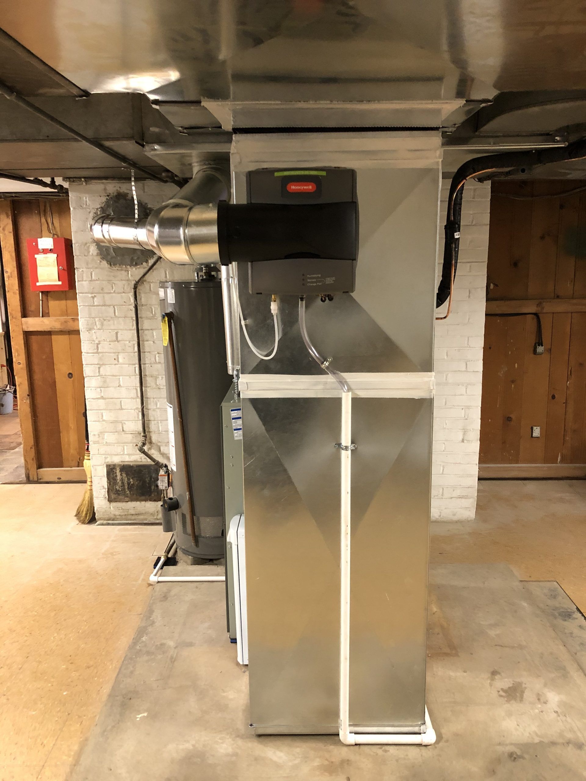 Furnace and humidifier in a basement. Ductwork and water heater are also visible.