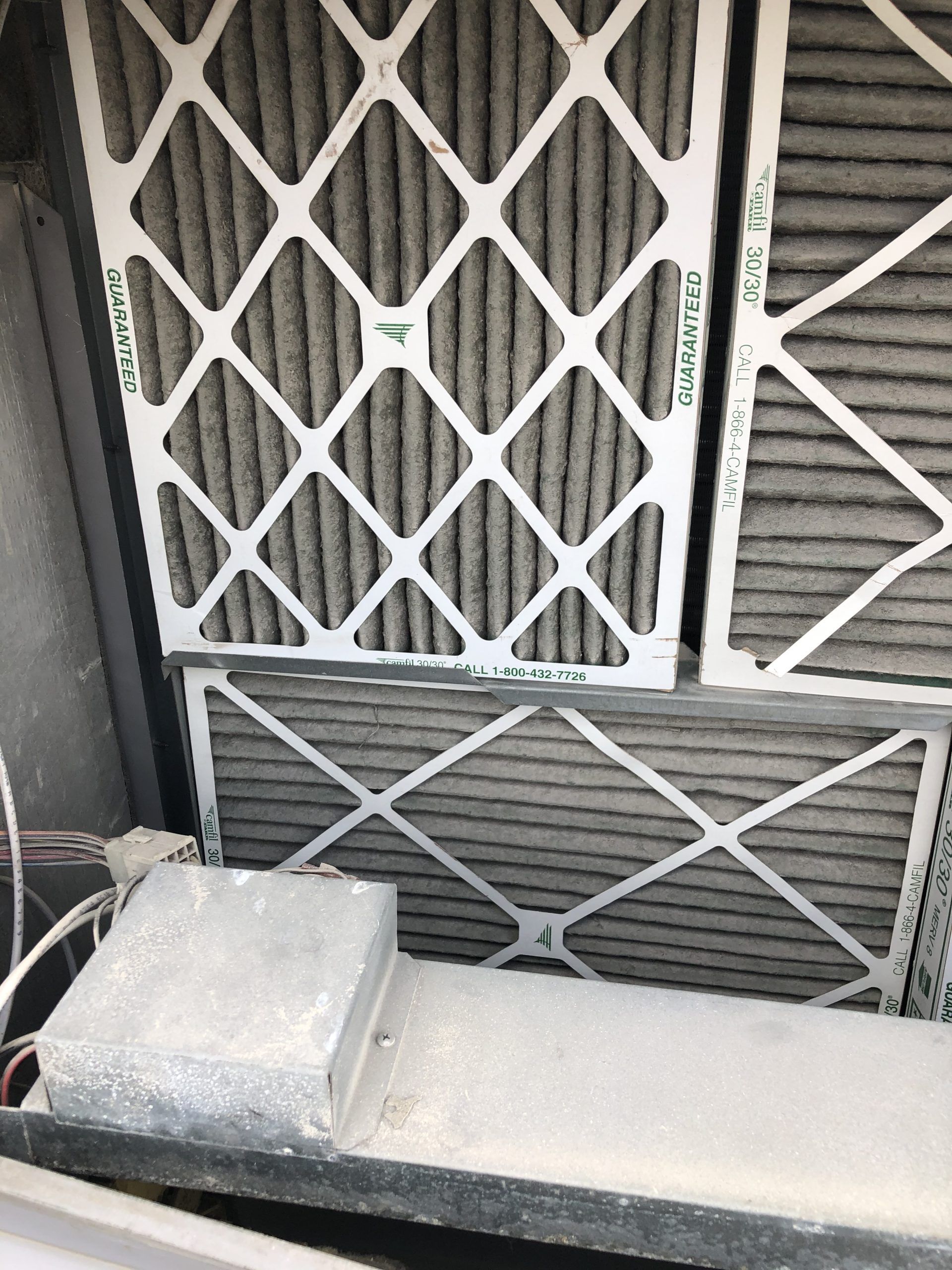 Dirty air filters in a metal frame, showing accumulated dust and debris.