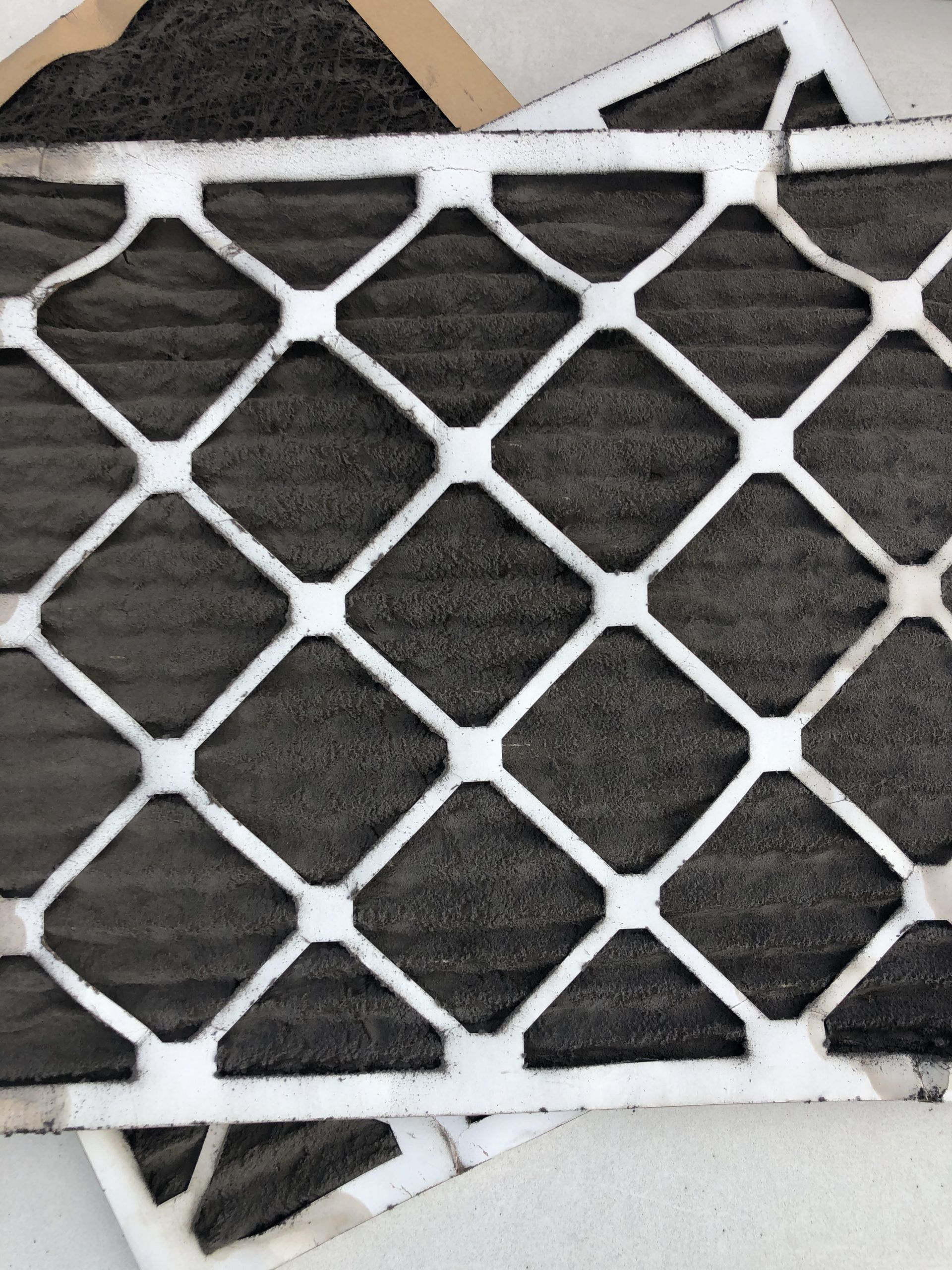 Used furnace air filters, showing a dark, dusty appearance within a white grid.