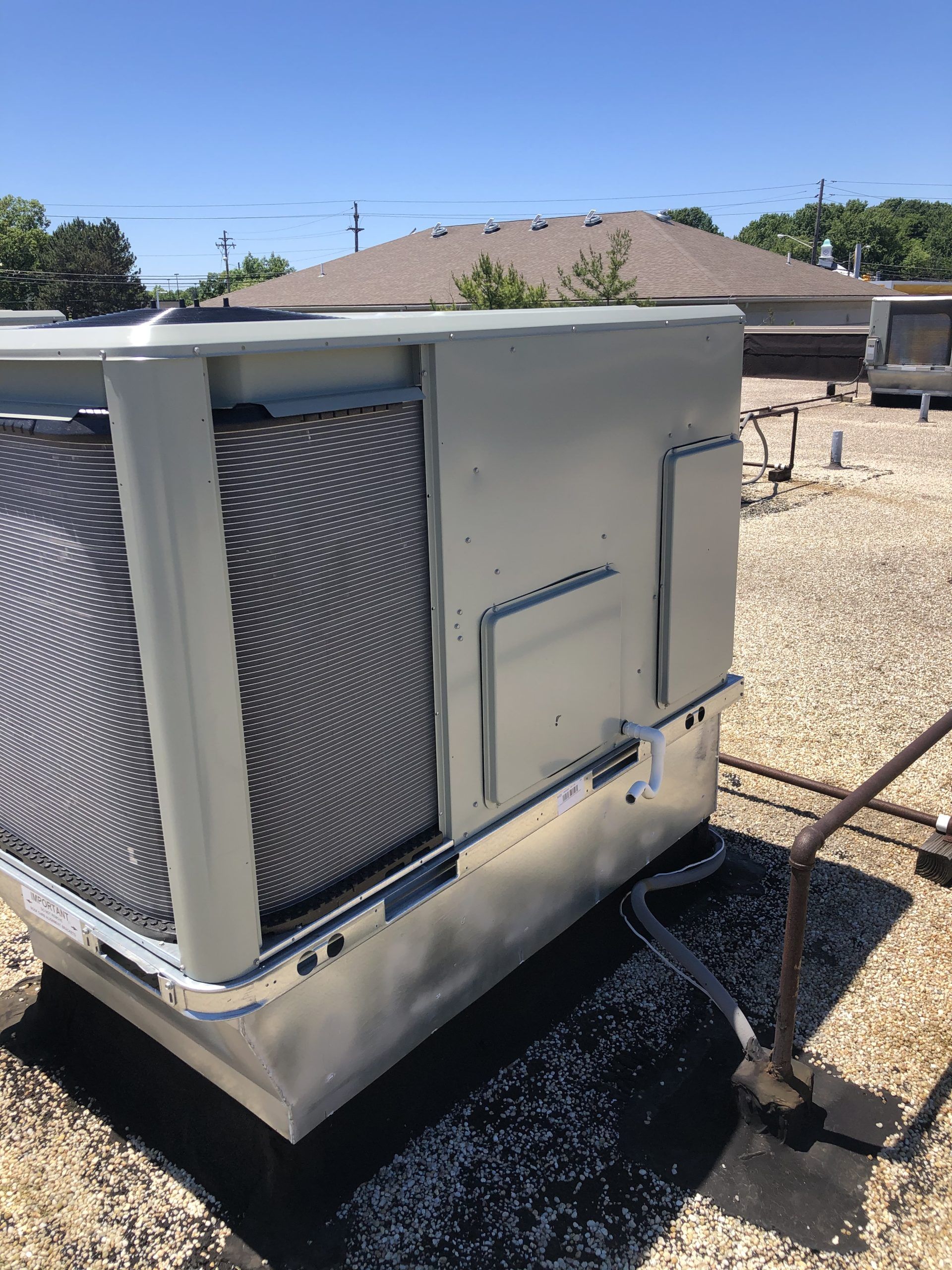 Rooftop HVAC unit on a sunny day. Gray metal box with vents, installed on a flat roof.
