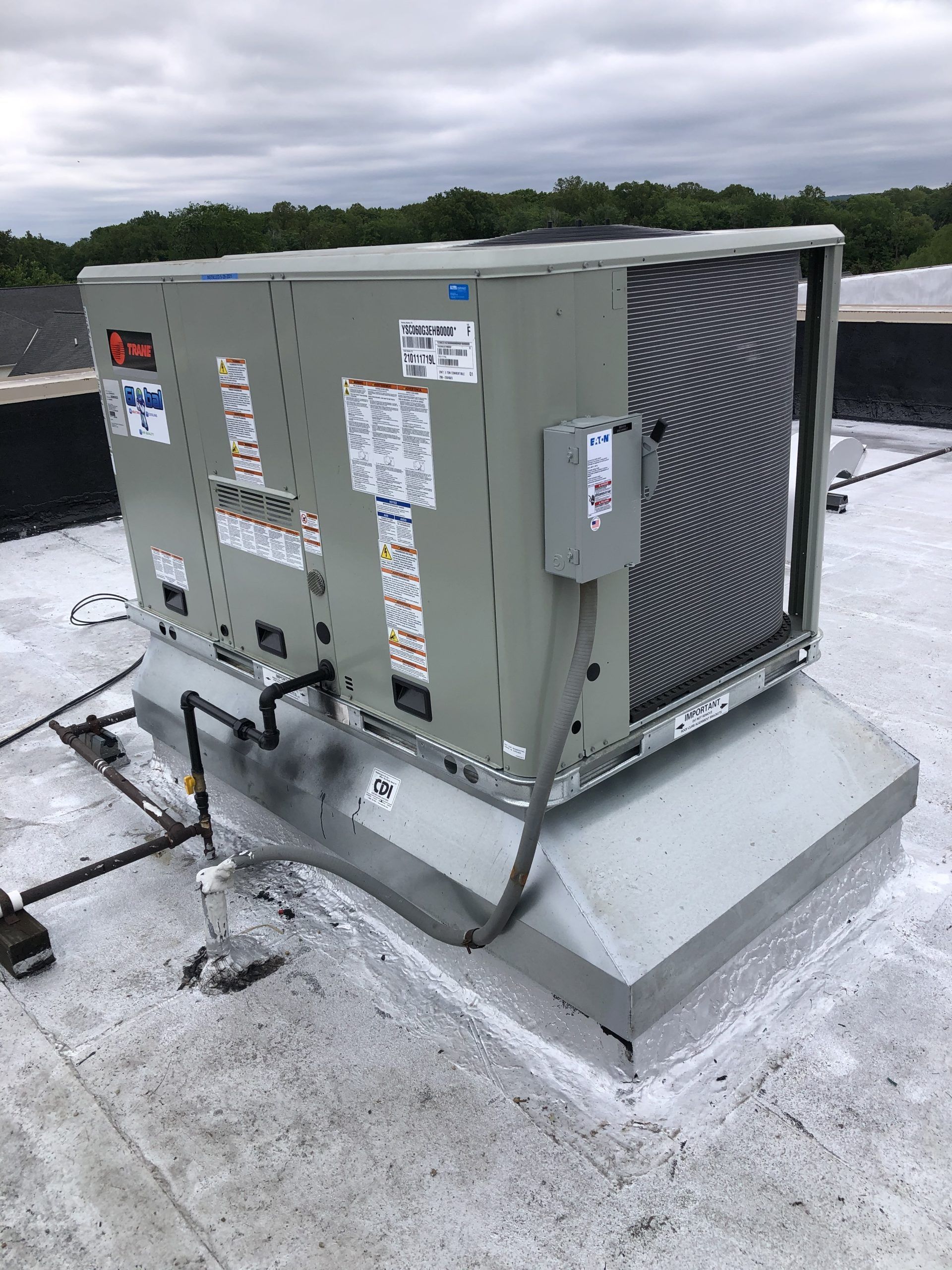 Rooftop HVAC unit on a gray roof; the unit is gray and has a large, black fan.