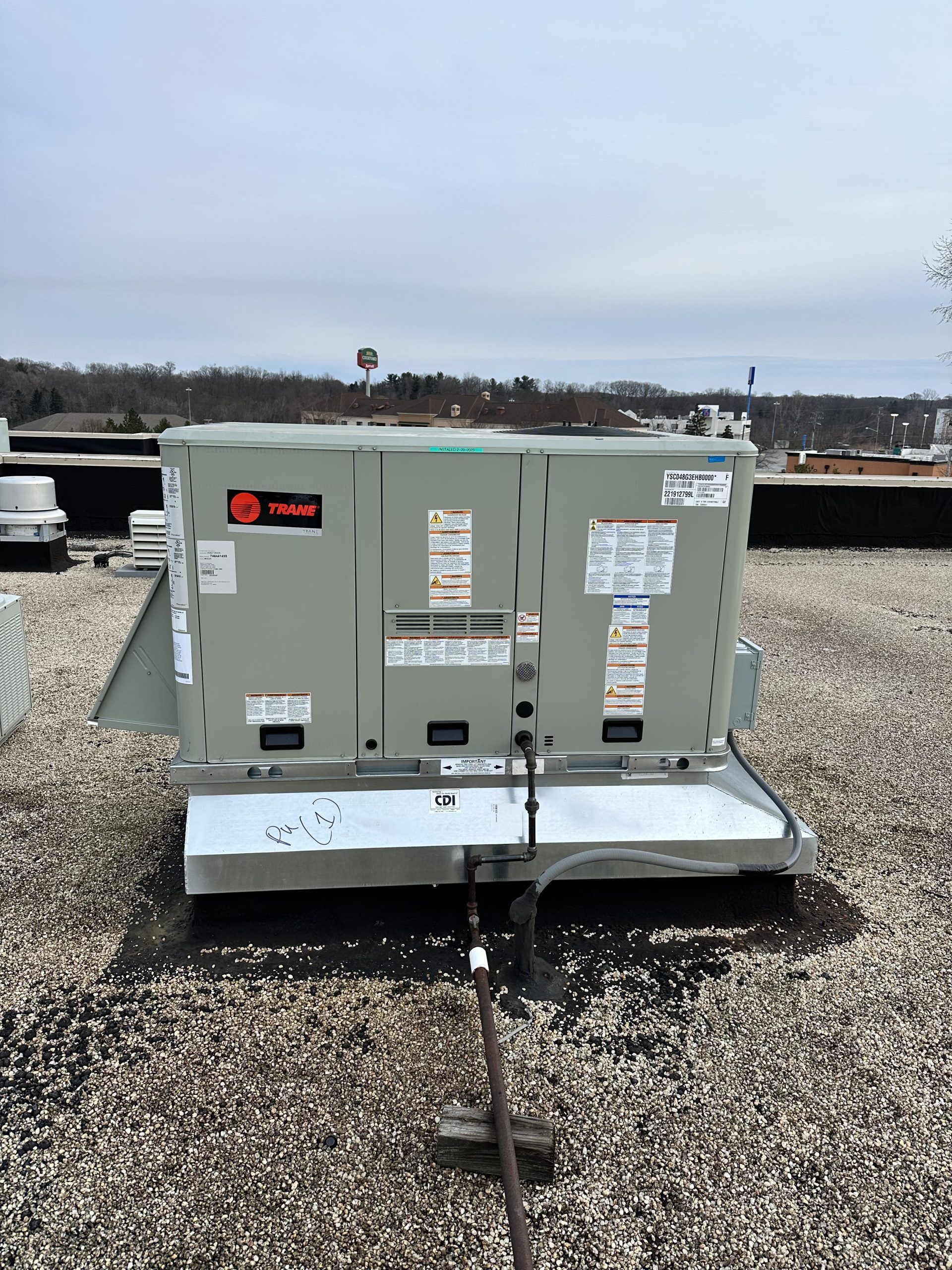 Gray Trane HVAC unit on a rooftop, overcast sky in background.