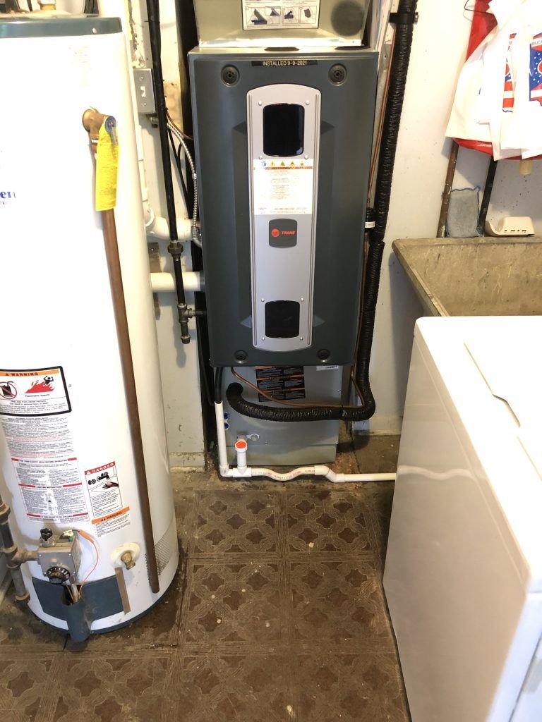 A gas water heater and a tankless water heater are in a laundry room next to a washing machine.