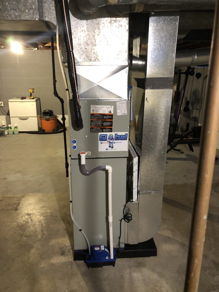 Furnace in a basement; gray metal and ductwork, with a condensate pump.