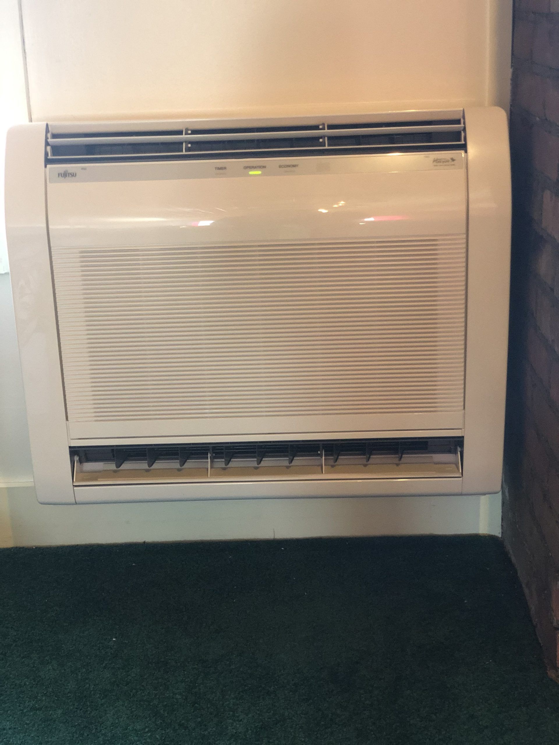 White wall-mounted air conditioning unit with horizontal vents.