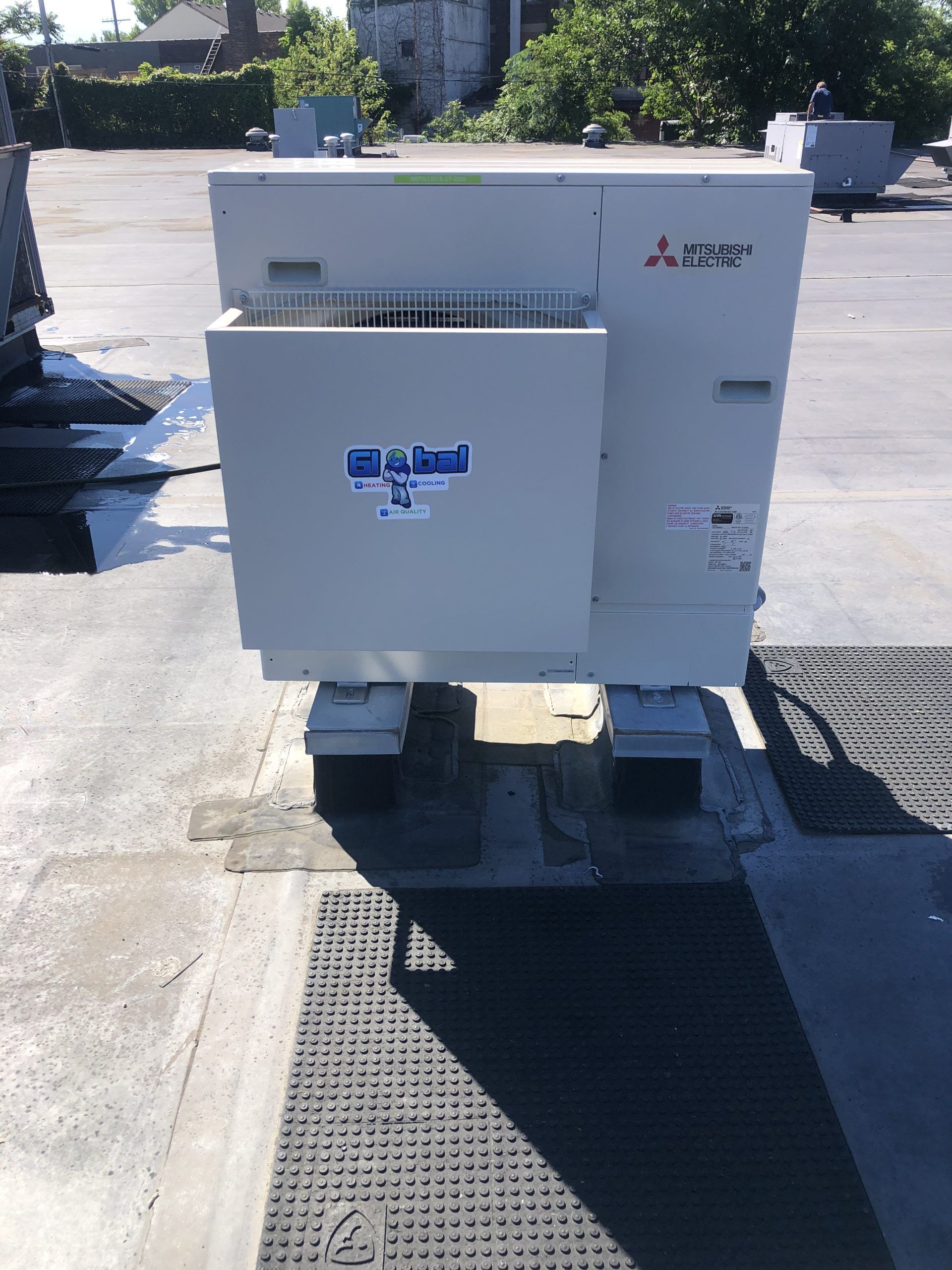 Mitsubishi air conditioning unit on a rooftop, light gray, with a smaller rectangular component in front.