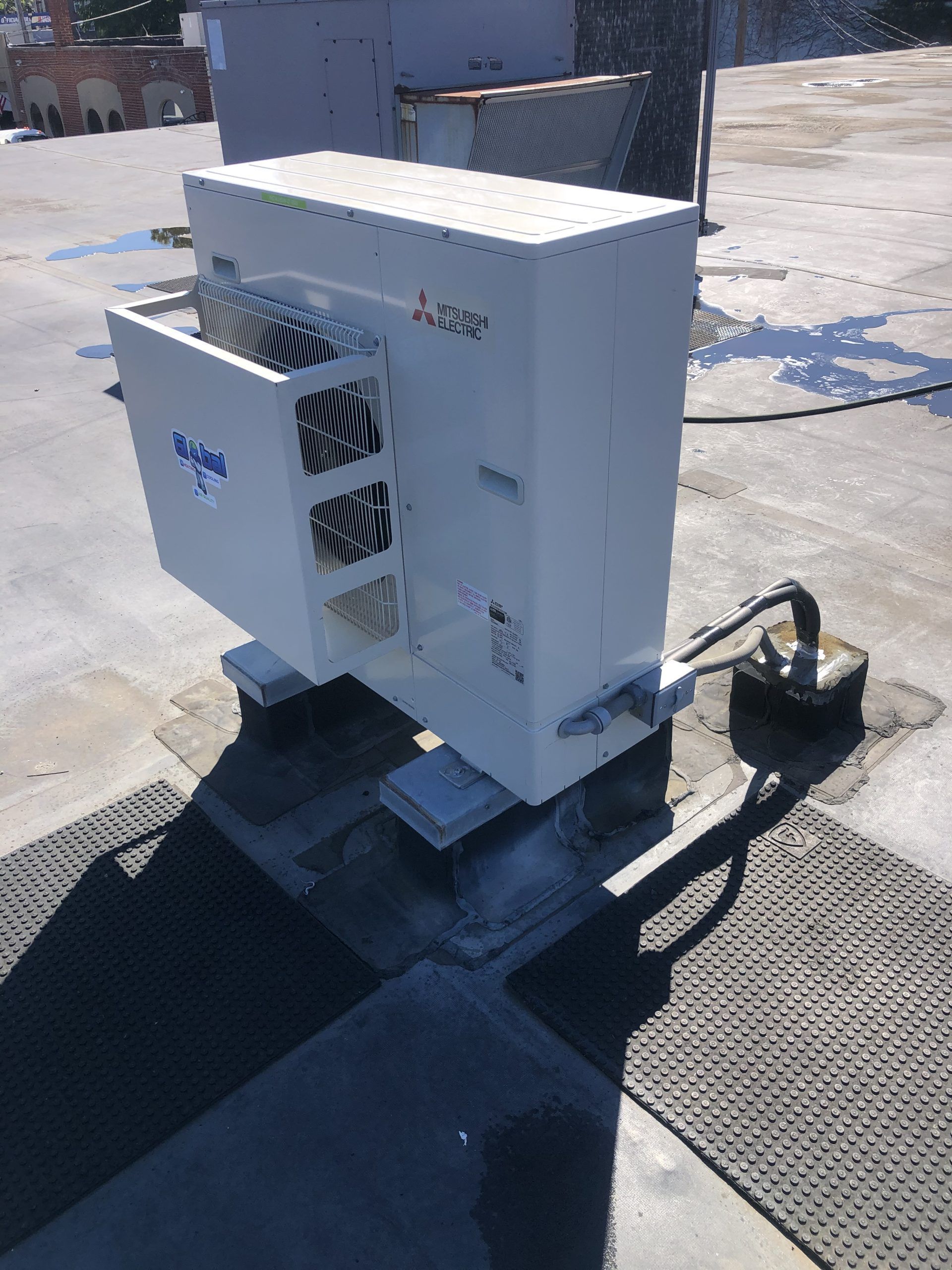 White Mitsubishi HVAC unit on rooftop, vents visible, mounted on blocks.