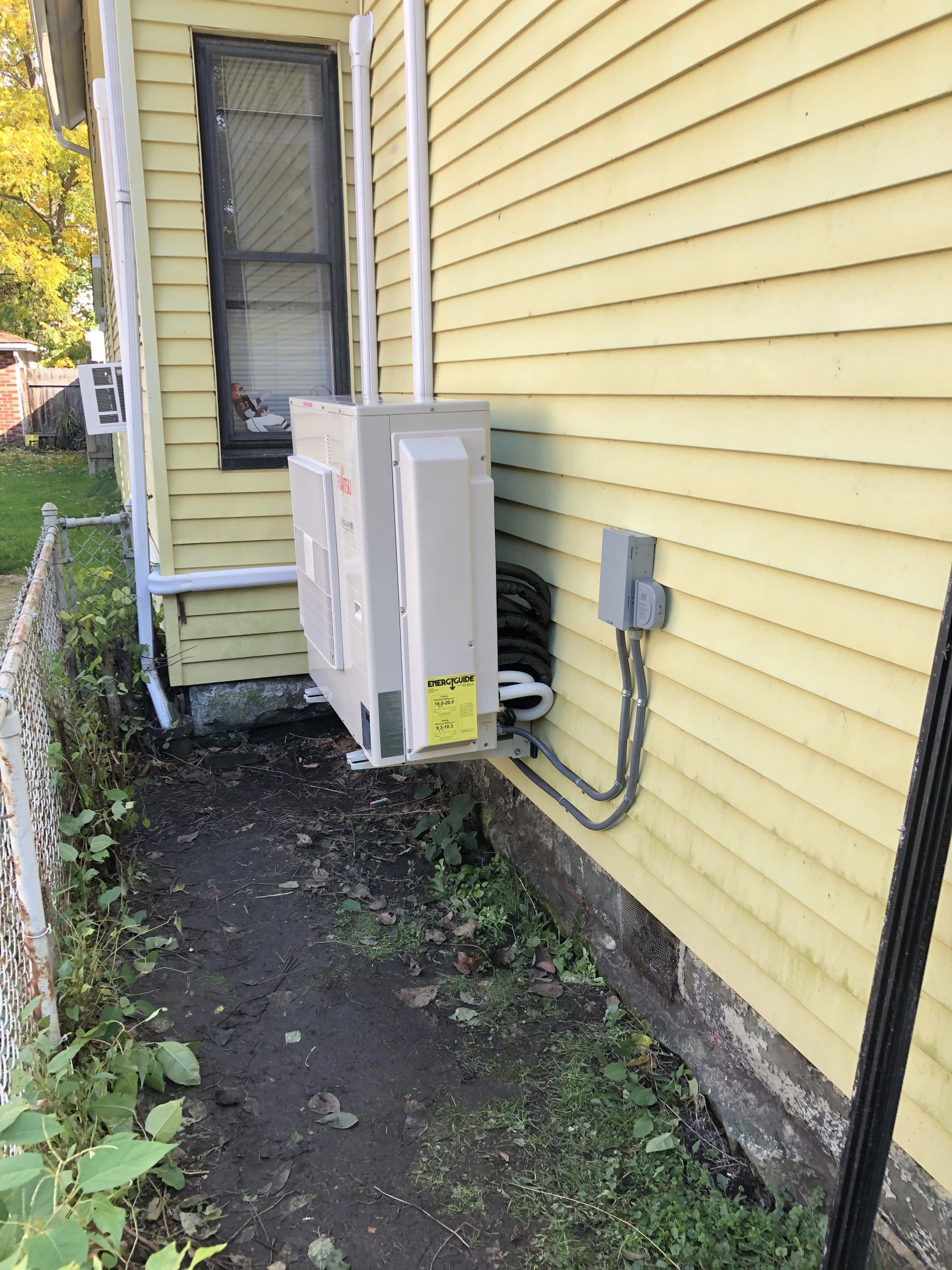 Yellow house exterior with air conditioning unit mounted near a window and electrical box.