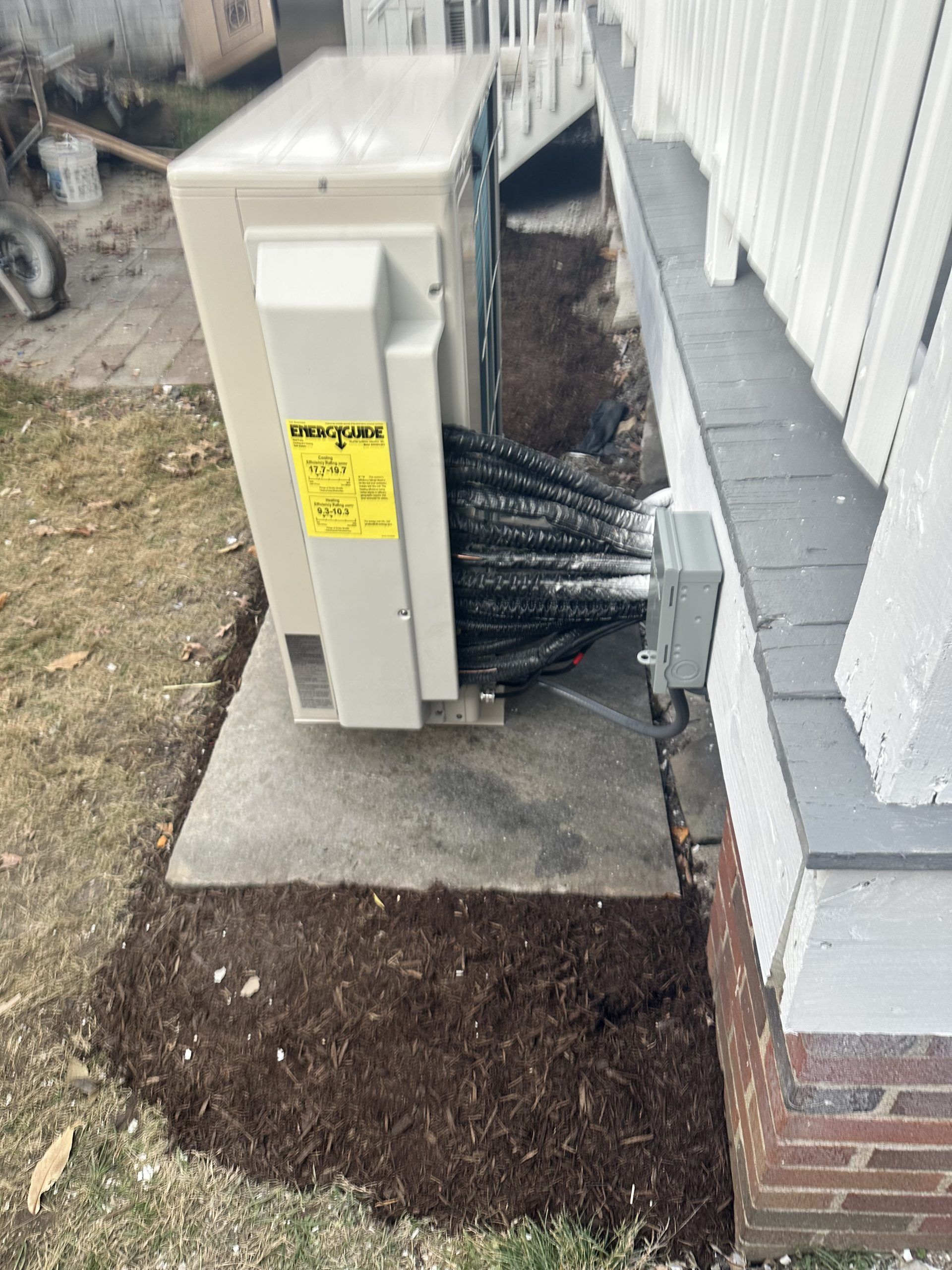 HVAC unit on a concrete pad near a house; mulch around the base.