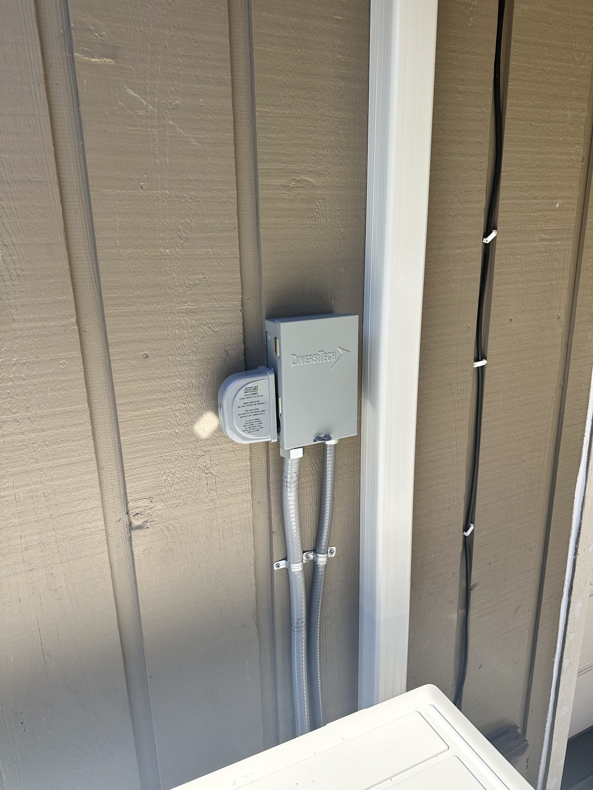 Electrical box mounted on a brown wall with two conduit pipes.