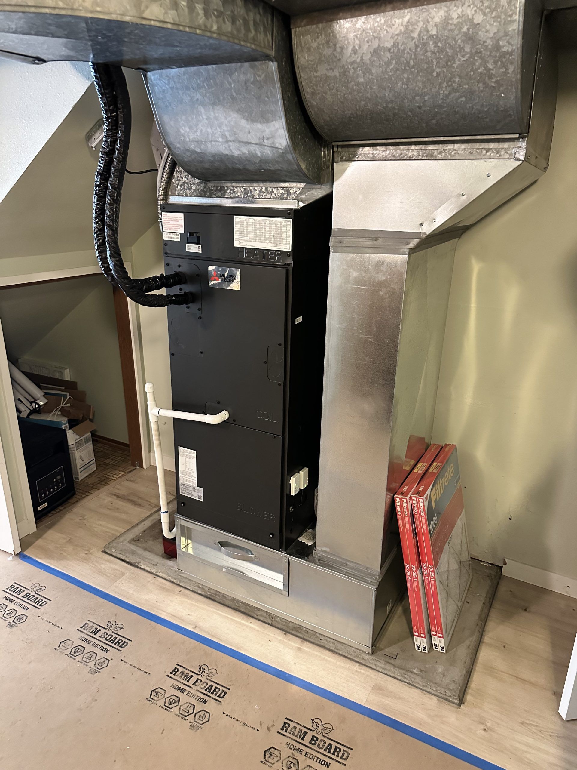 HVAC system in a residential setting with ductwork, on plywood flooring, and construction supplies.