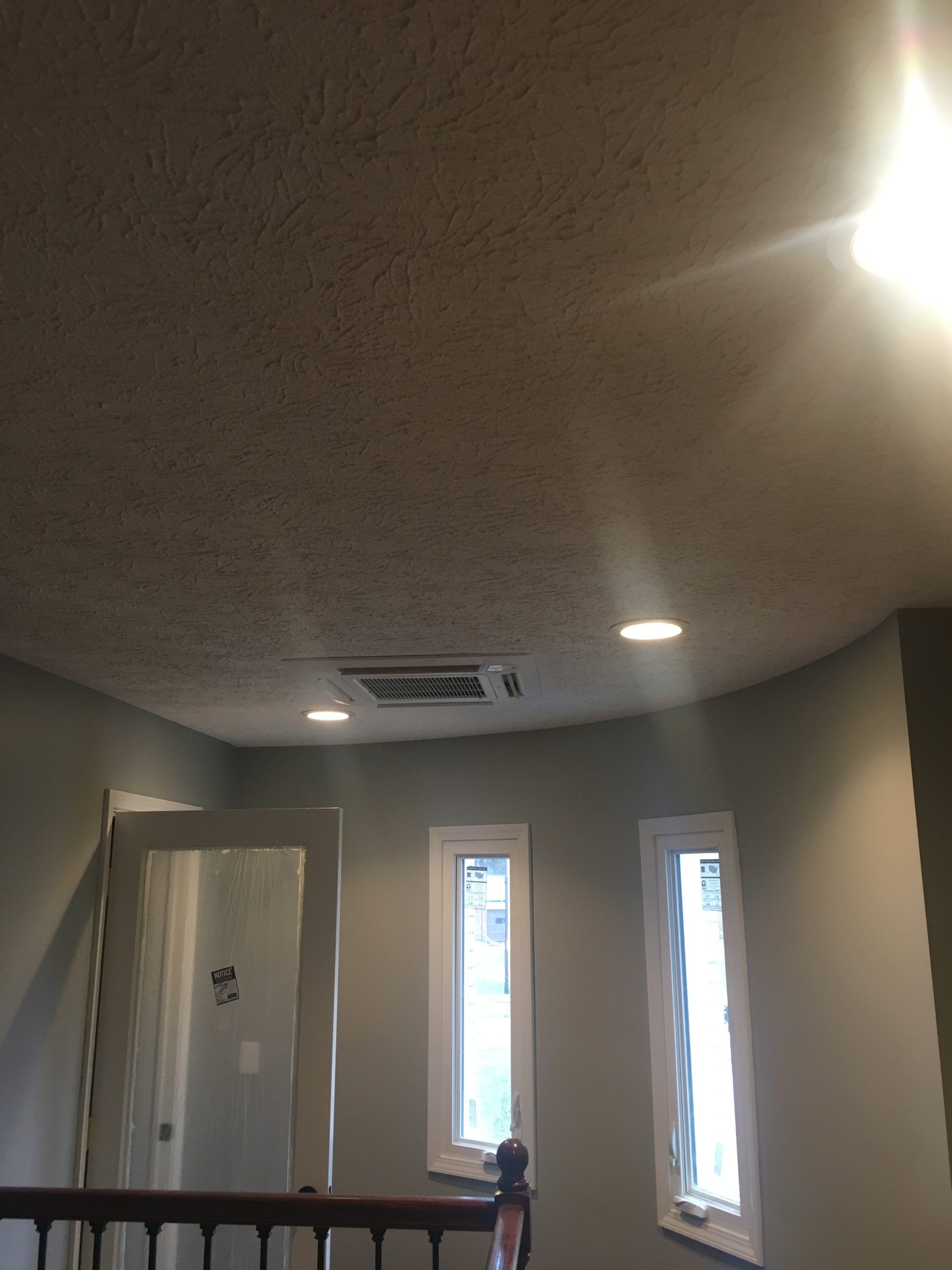 Room with light blue walls, two windows, and a doorway. Recessed lights and a ceiling vent are visible.