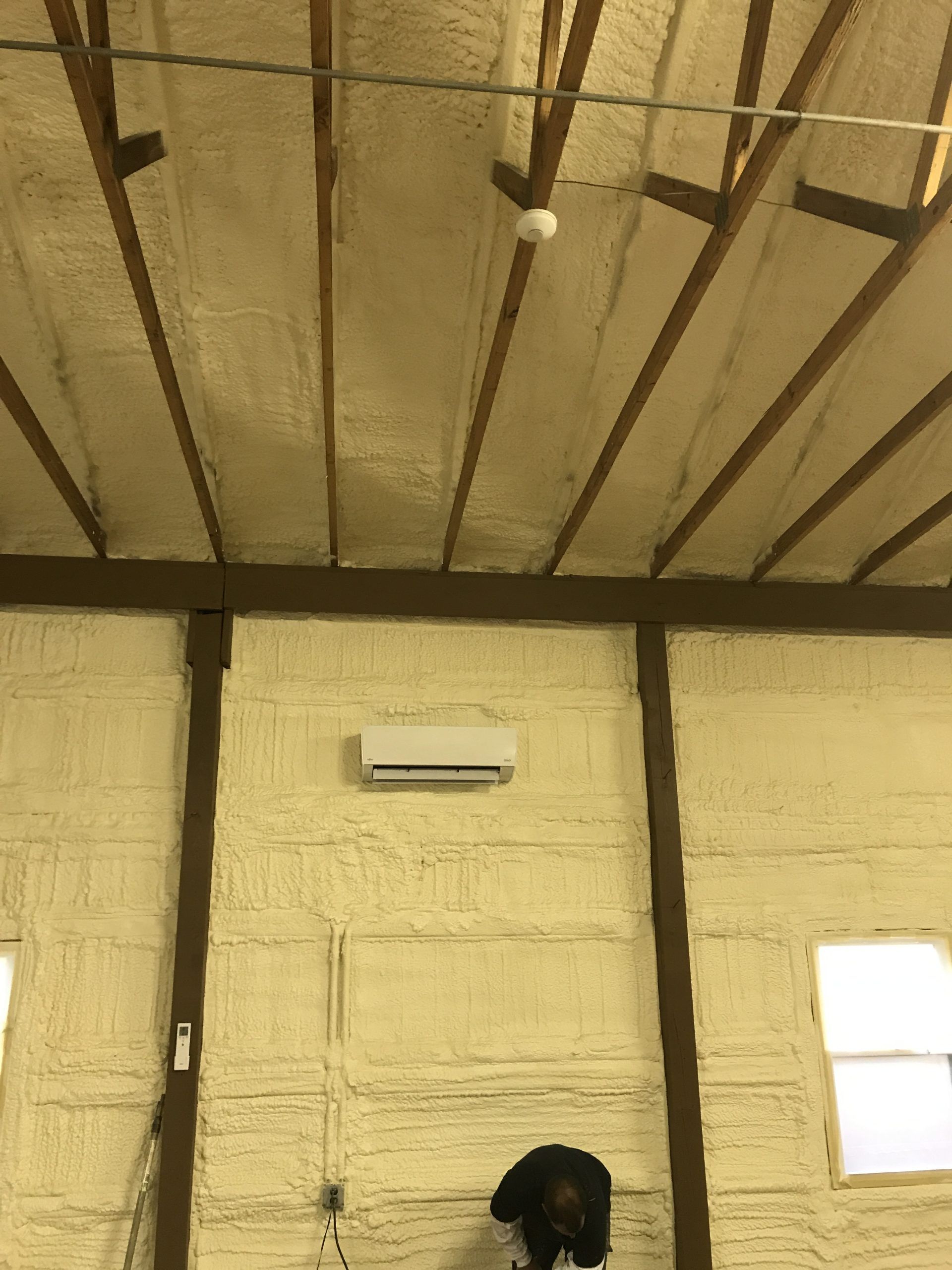 White ball is bouncing in an indoor building with yellow insulation and exposed beams.