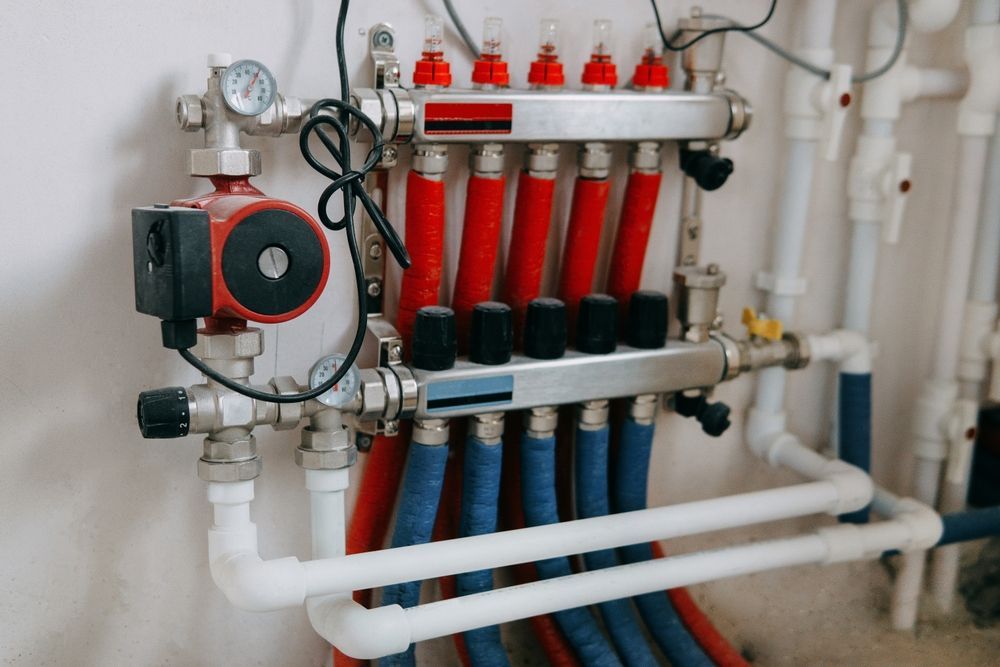 Heating system manifold with red and blue pipes and a pump.