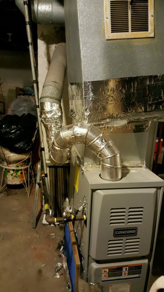 Furnace with silver ductwork in a basement setting.