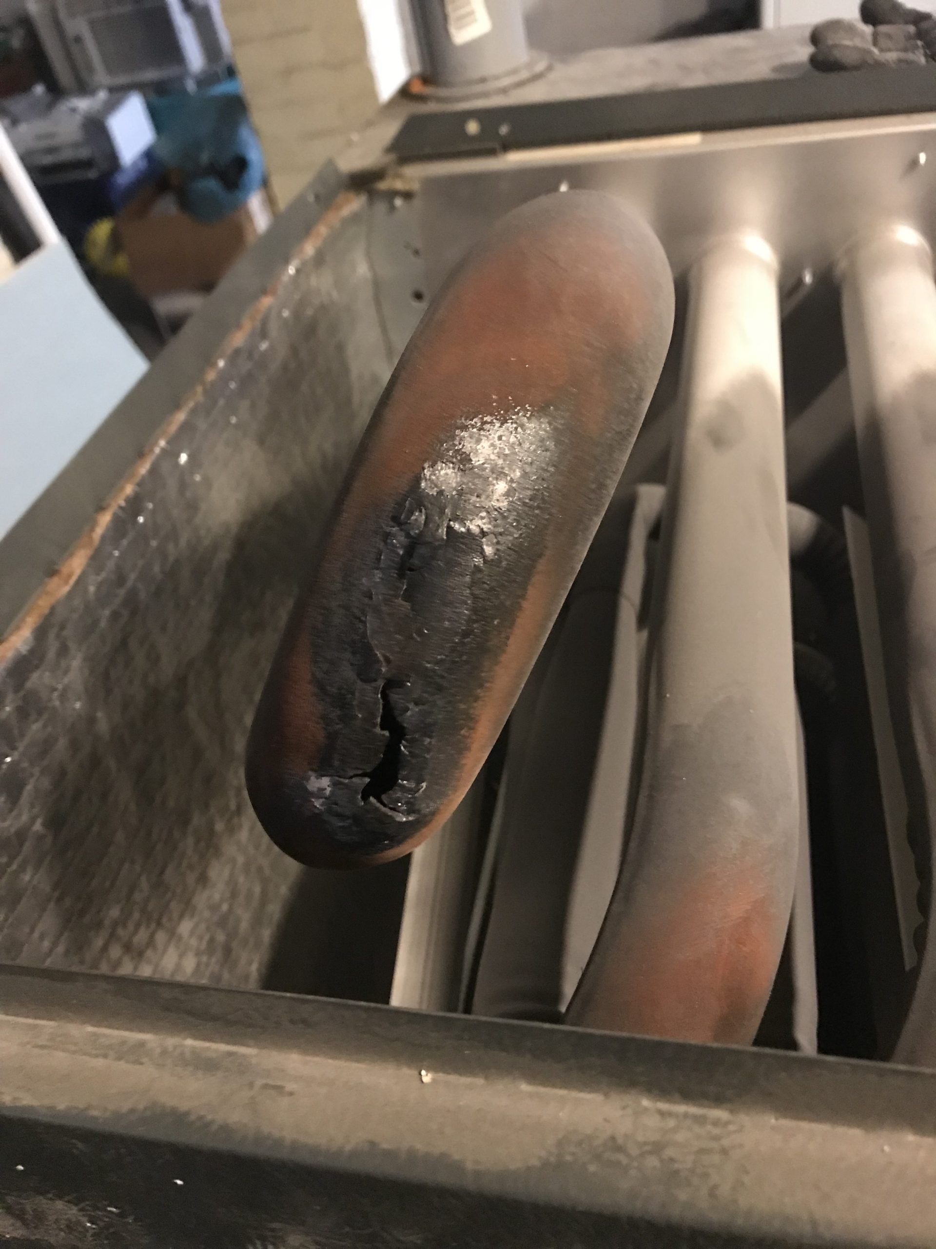 Damaged furnace heat exchanger tube with a burnt hole.