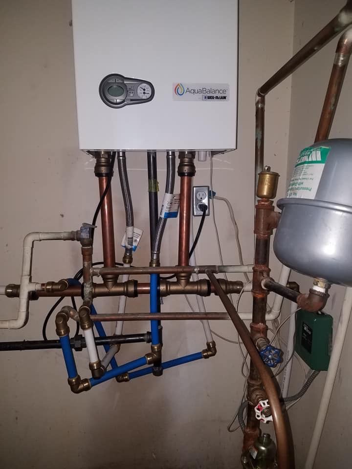 A wall-mounted, white gas-fired water heater with copper and blue pipes.