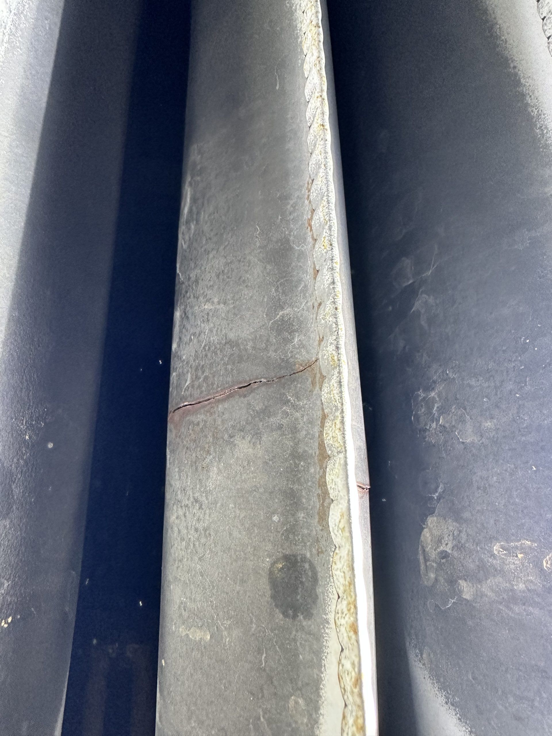 Close-up of a dark, textured surface with a thin, reddish crack running across it.