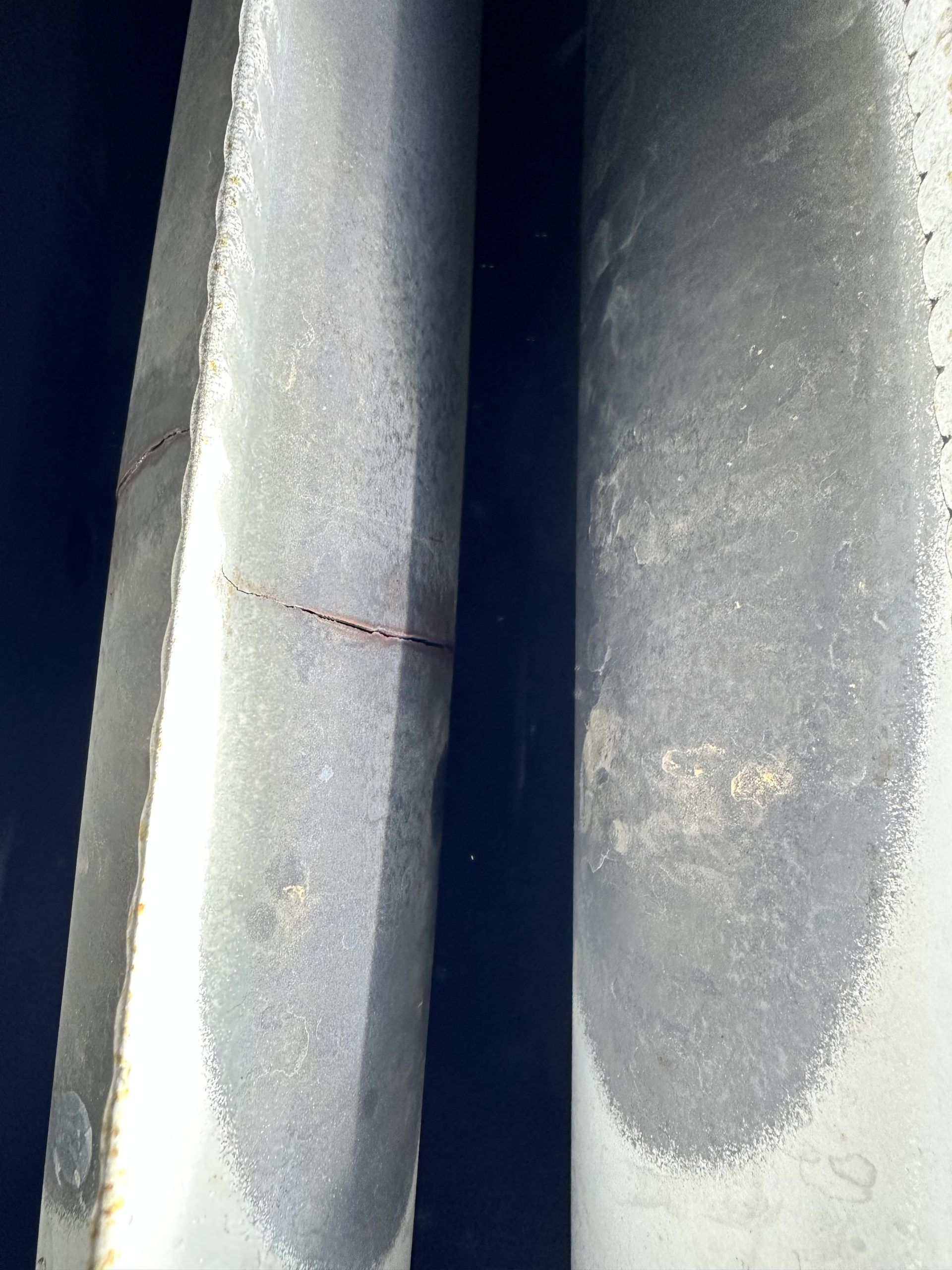 Two weathered, cylindrical poles with a dark space between them.