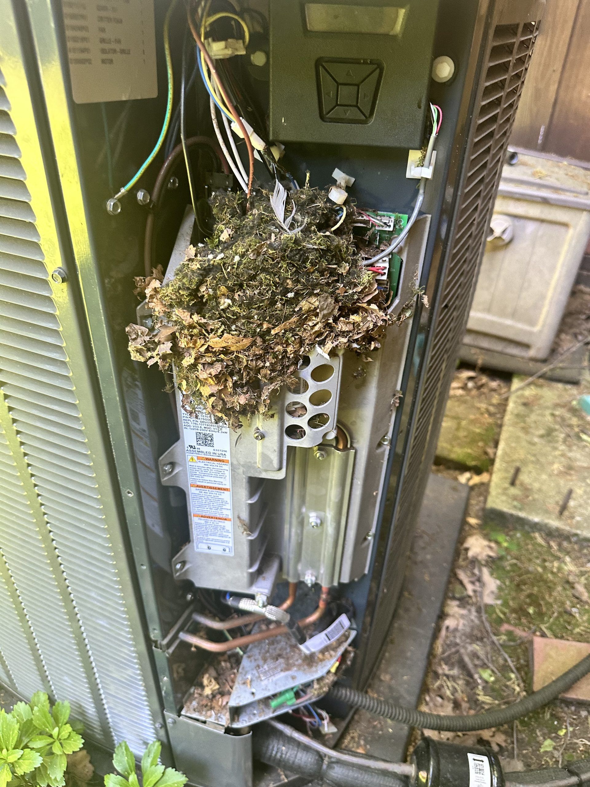 Damaged outdoor air conditioning unit with charred debris and exposed components.