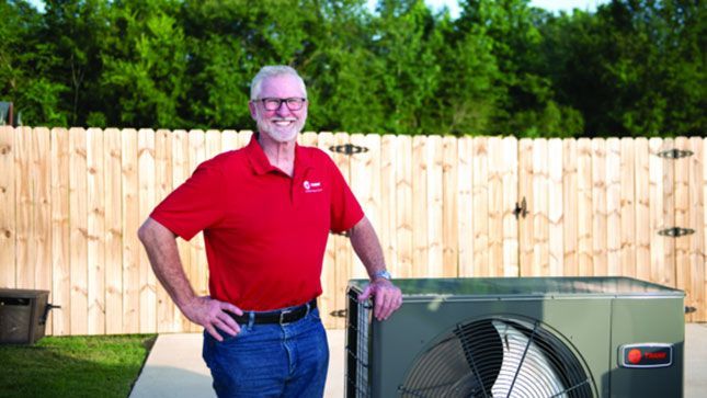 Woman with arms raised, happy under an air conditioner in a white office.
