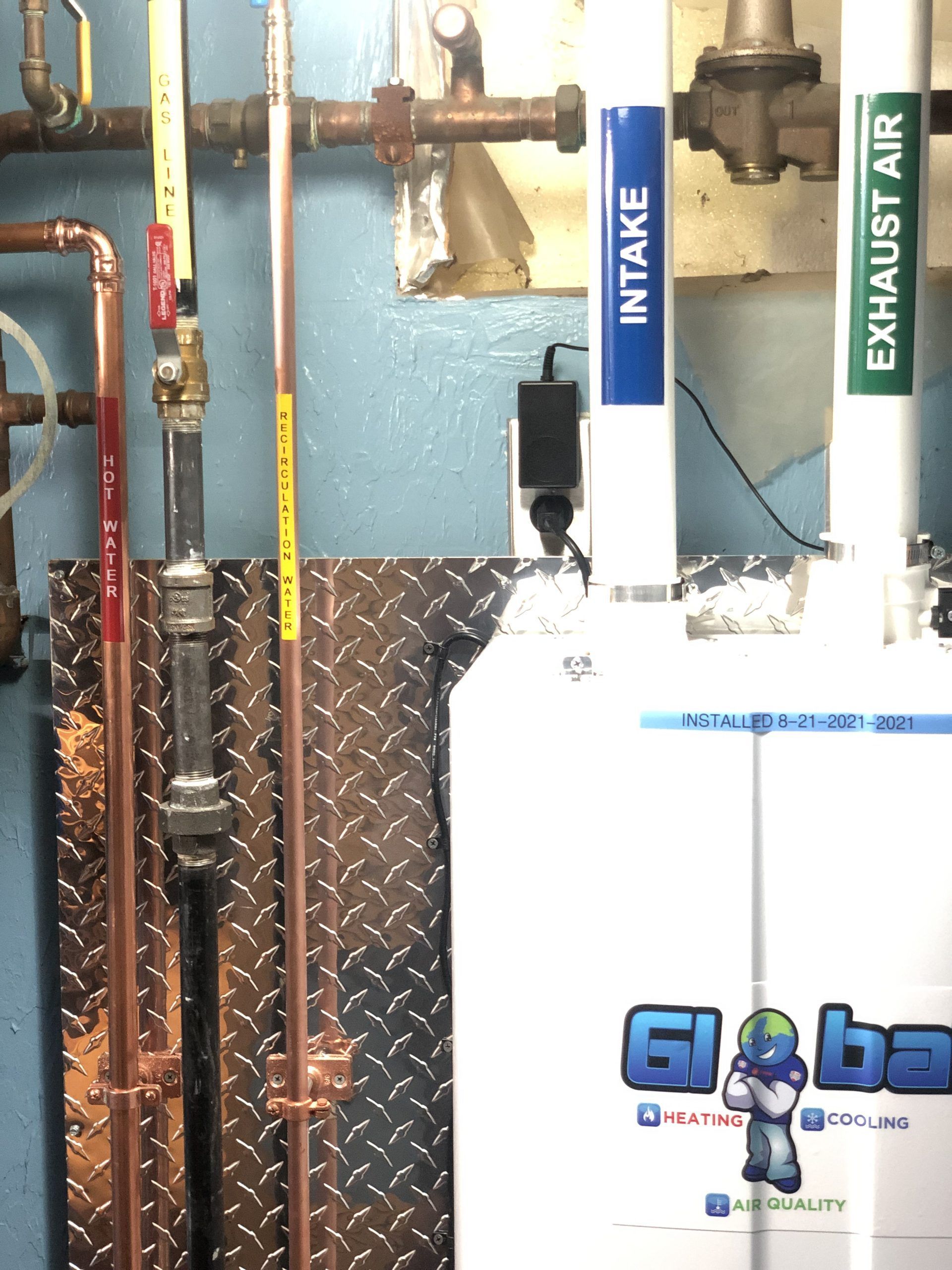 Close-up of boiler with intake and exhaust pipes; copper piping, blue and white labels.