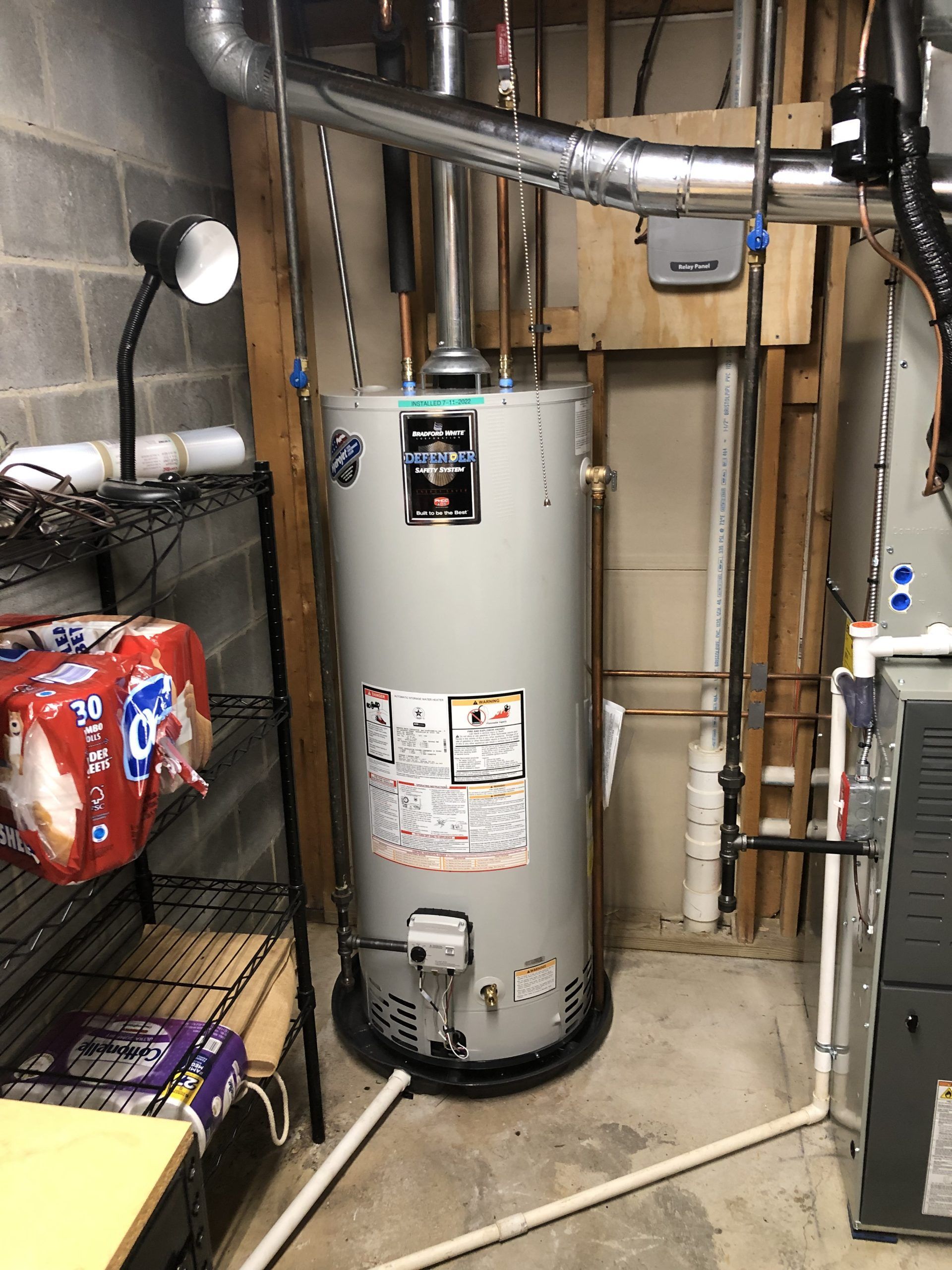 Water heater in a utility room; pipes and ductwork visible.