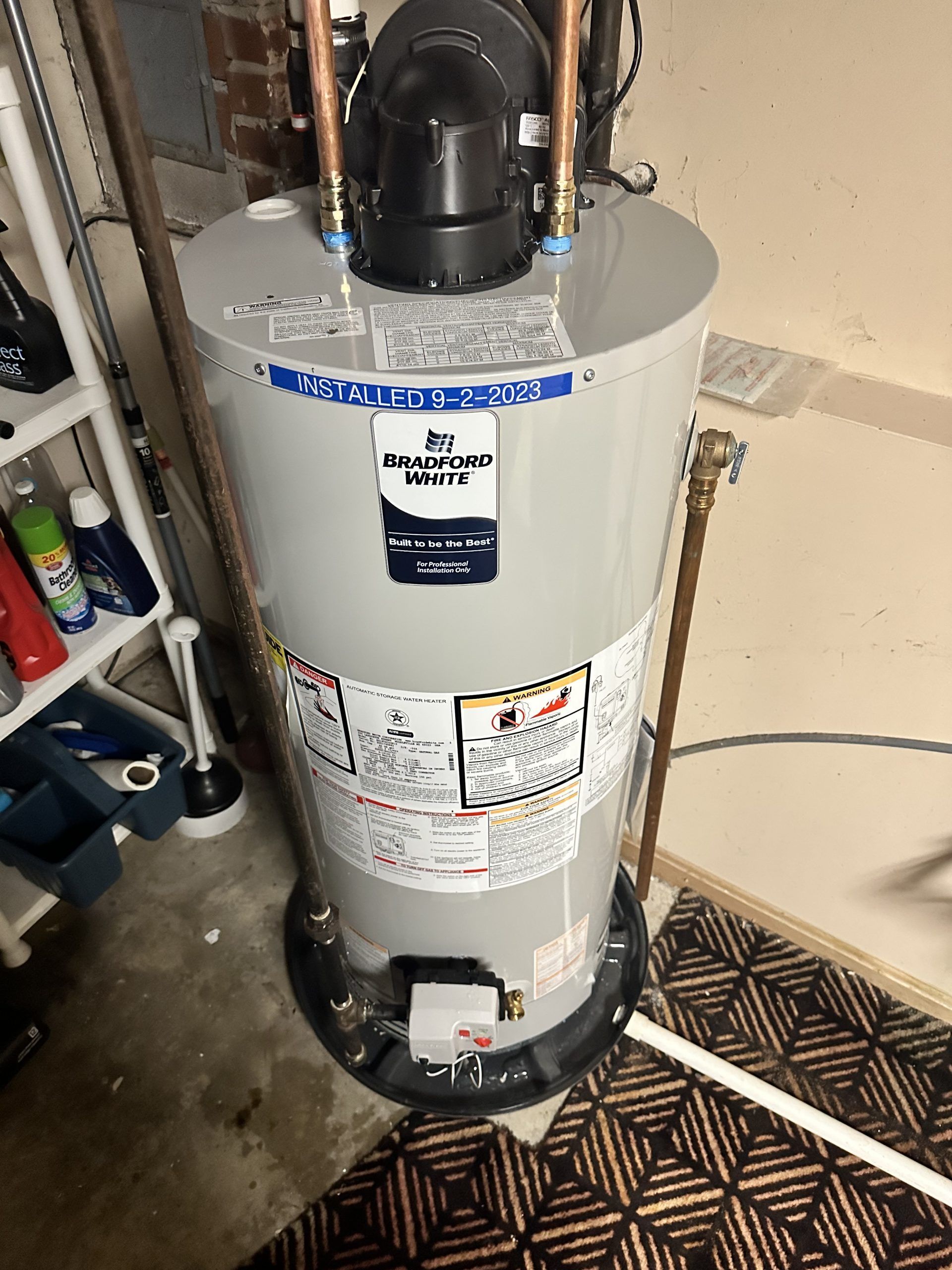 A tall, gray water heater with copper pipes in a utility room.
