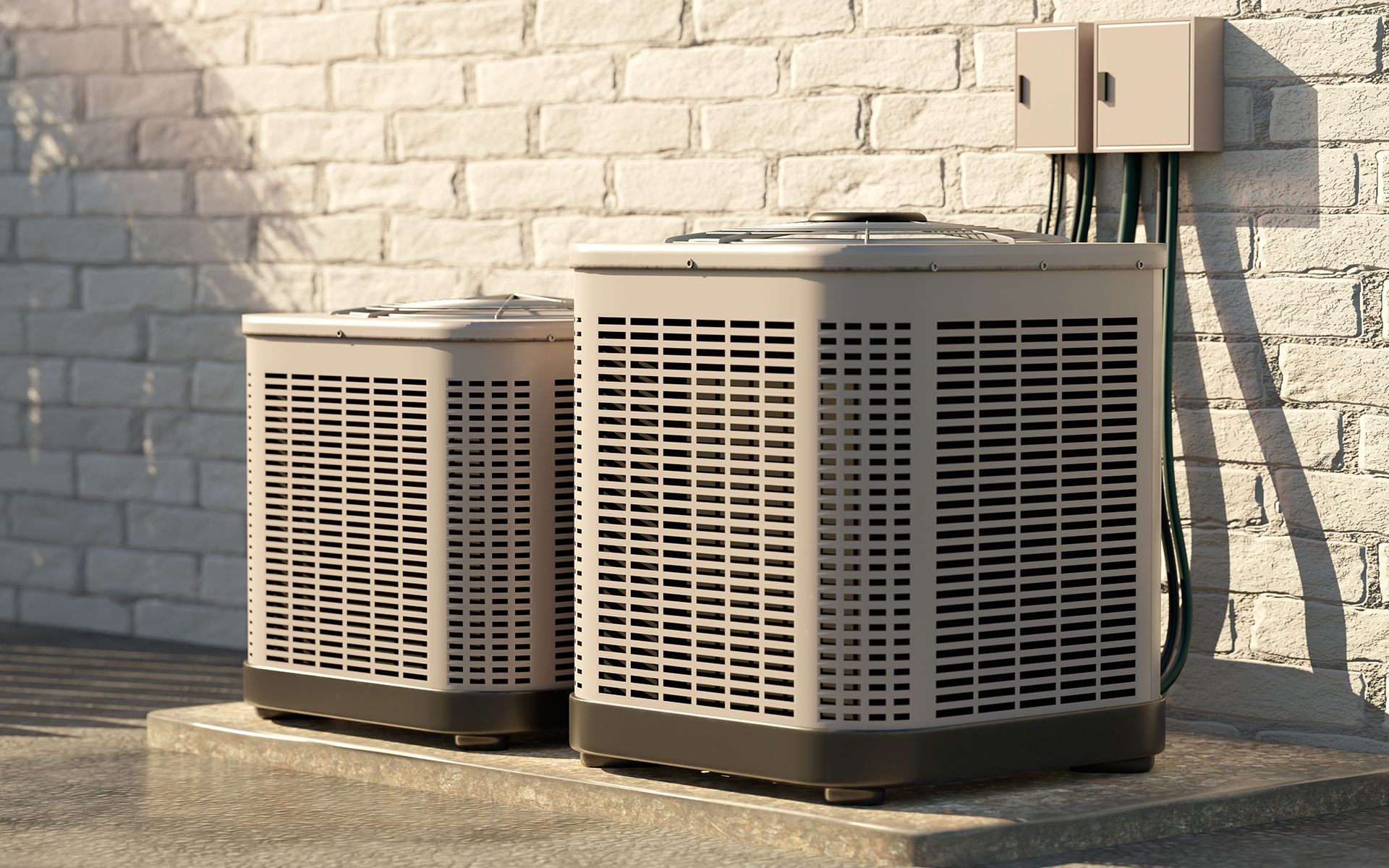Two beige air conditioning units on a concrete pad next to a brick wall.