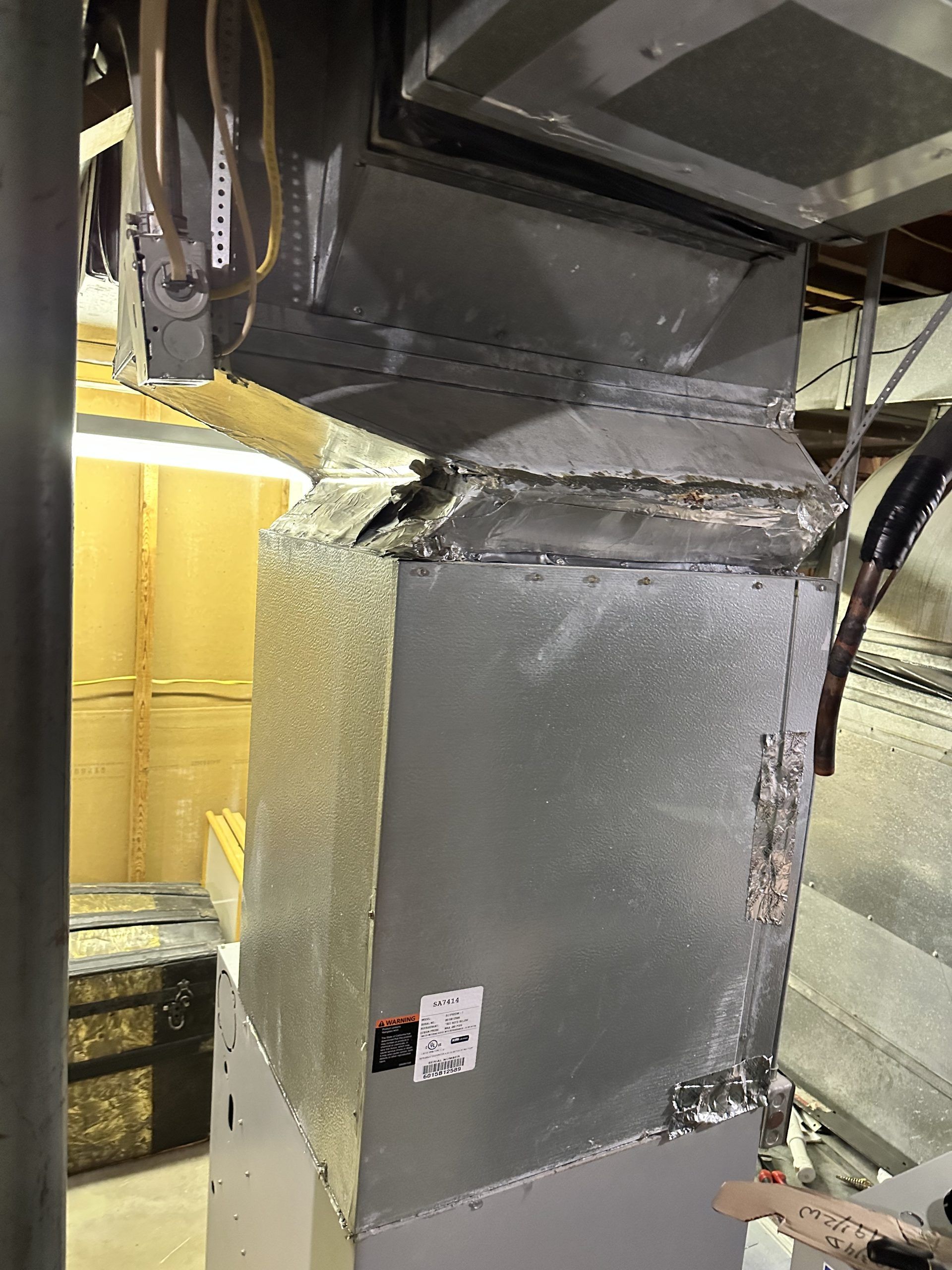 Metal HVAC ductwork with insulation in a basement.