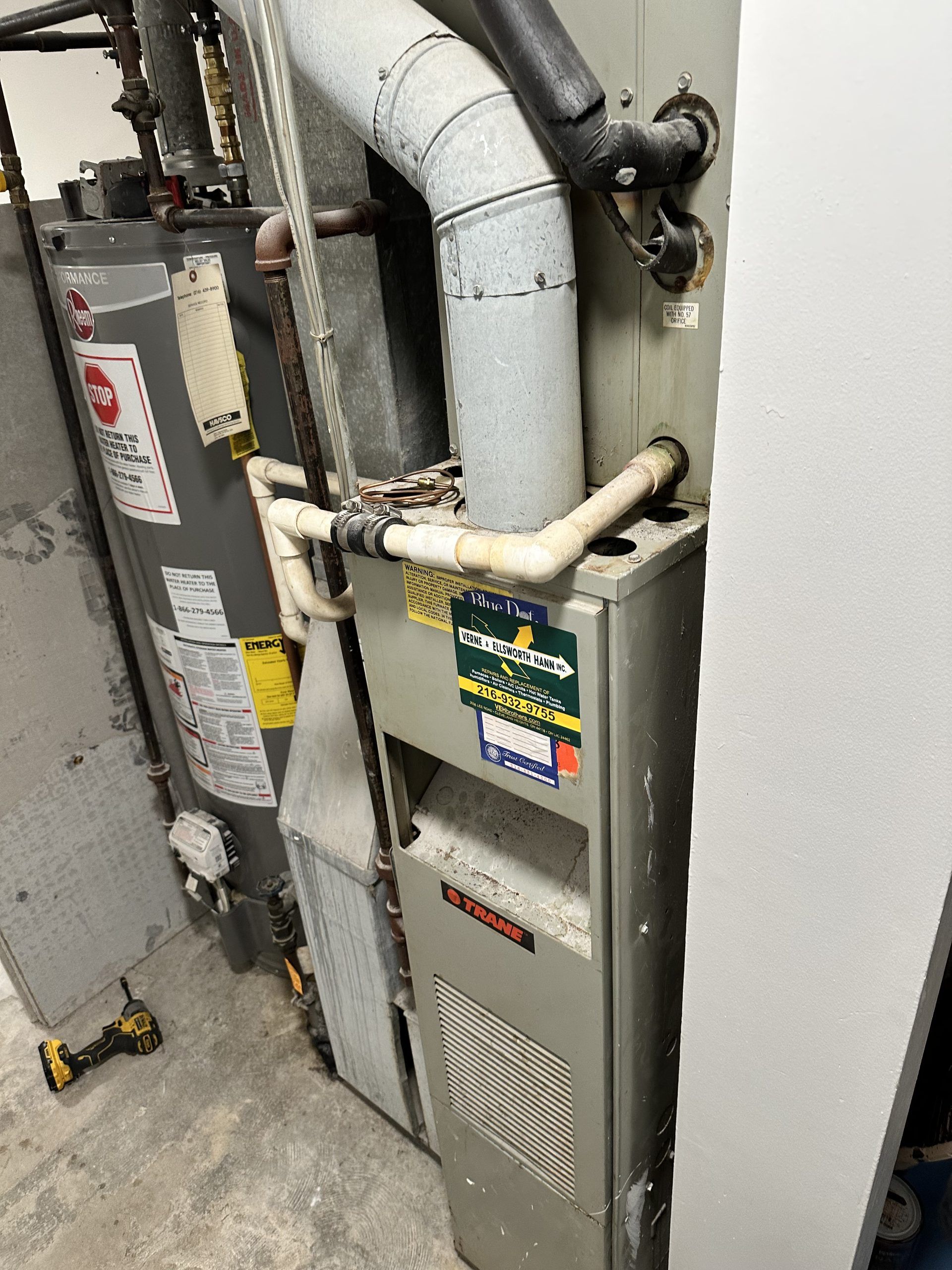 Furnace and water heater in a utility room. Grey metal appliances with white exhaust pipes.