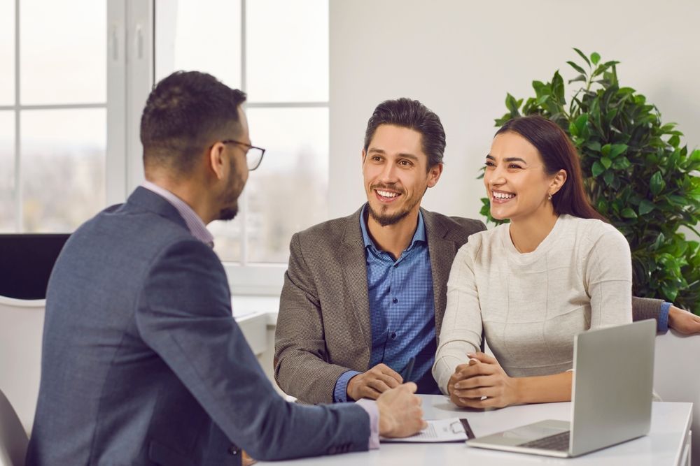 A financial advisor meeting with a smiling couple at a desk.
