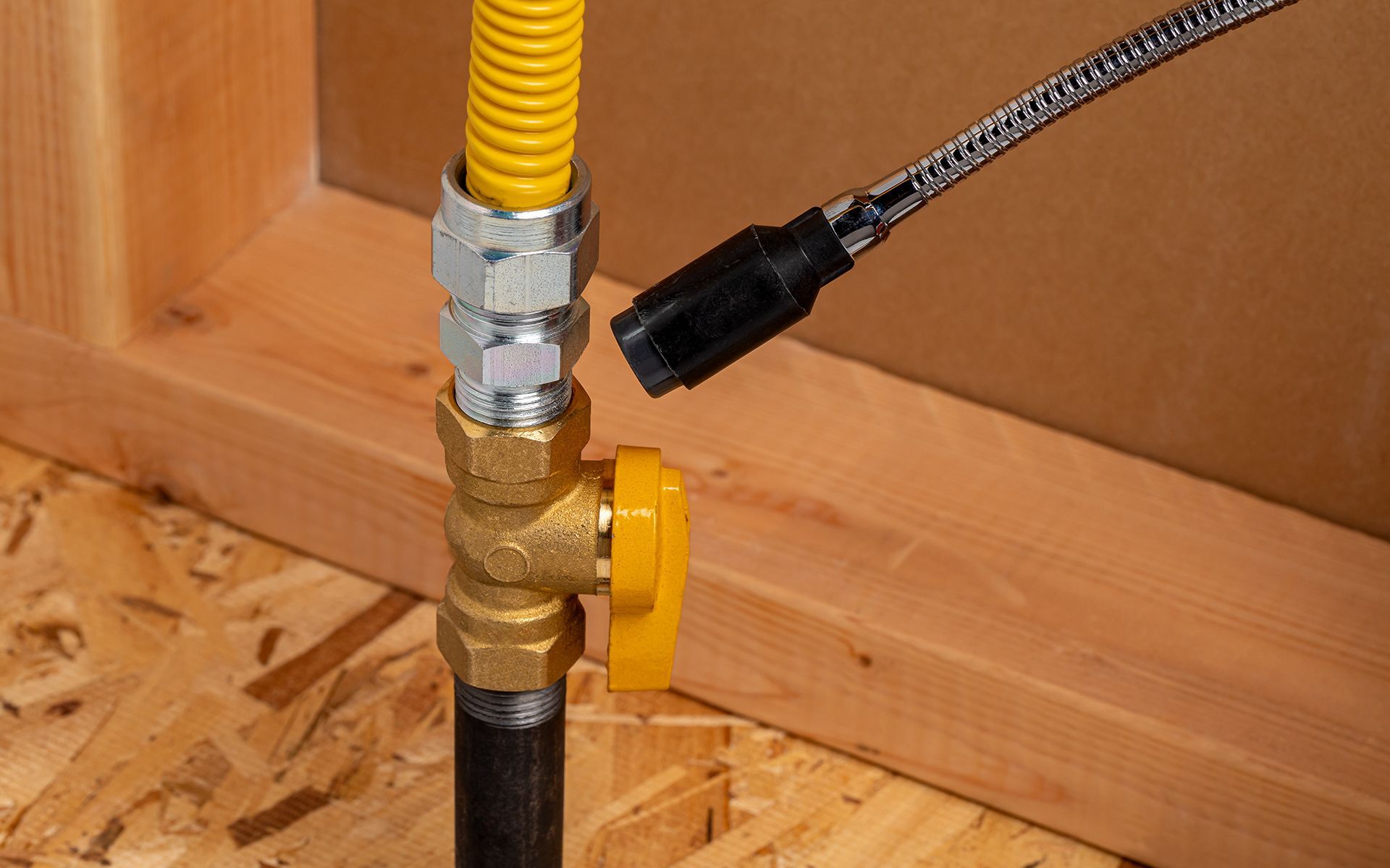 Gas valve with yellow handle and connected flexible yellow gas line. A black plug is inserted.