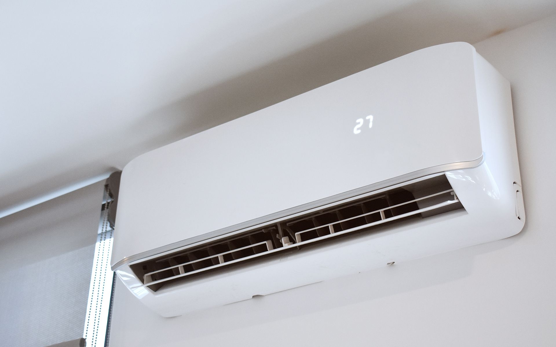 White wall-mounted air conditioner unit displaying the number 21 against a white wall.