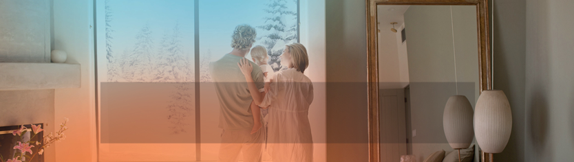 Woman relaxing while another person prepares food in a kitchen. Yellow flowers are in front.