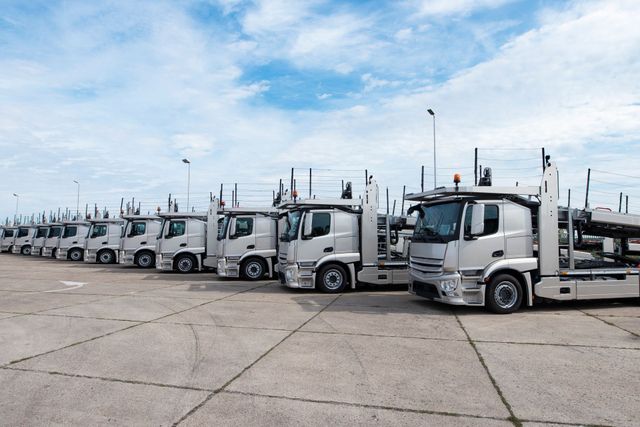 A row of white trucks are parked in a parking lot.