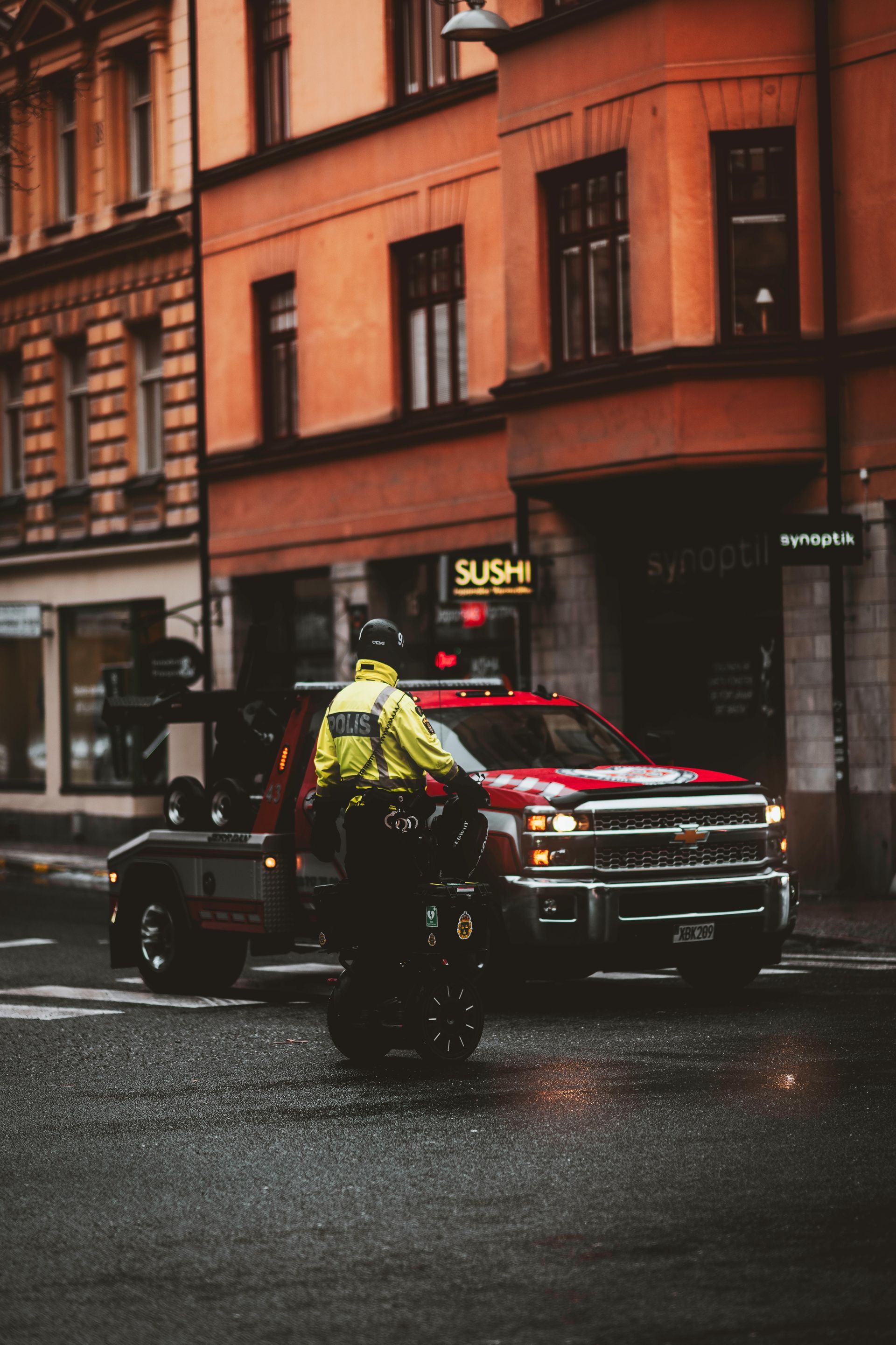A police officer is riding a motorcycle in front of a red truck.