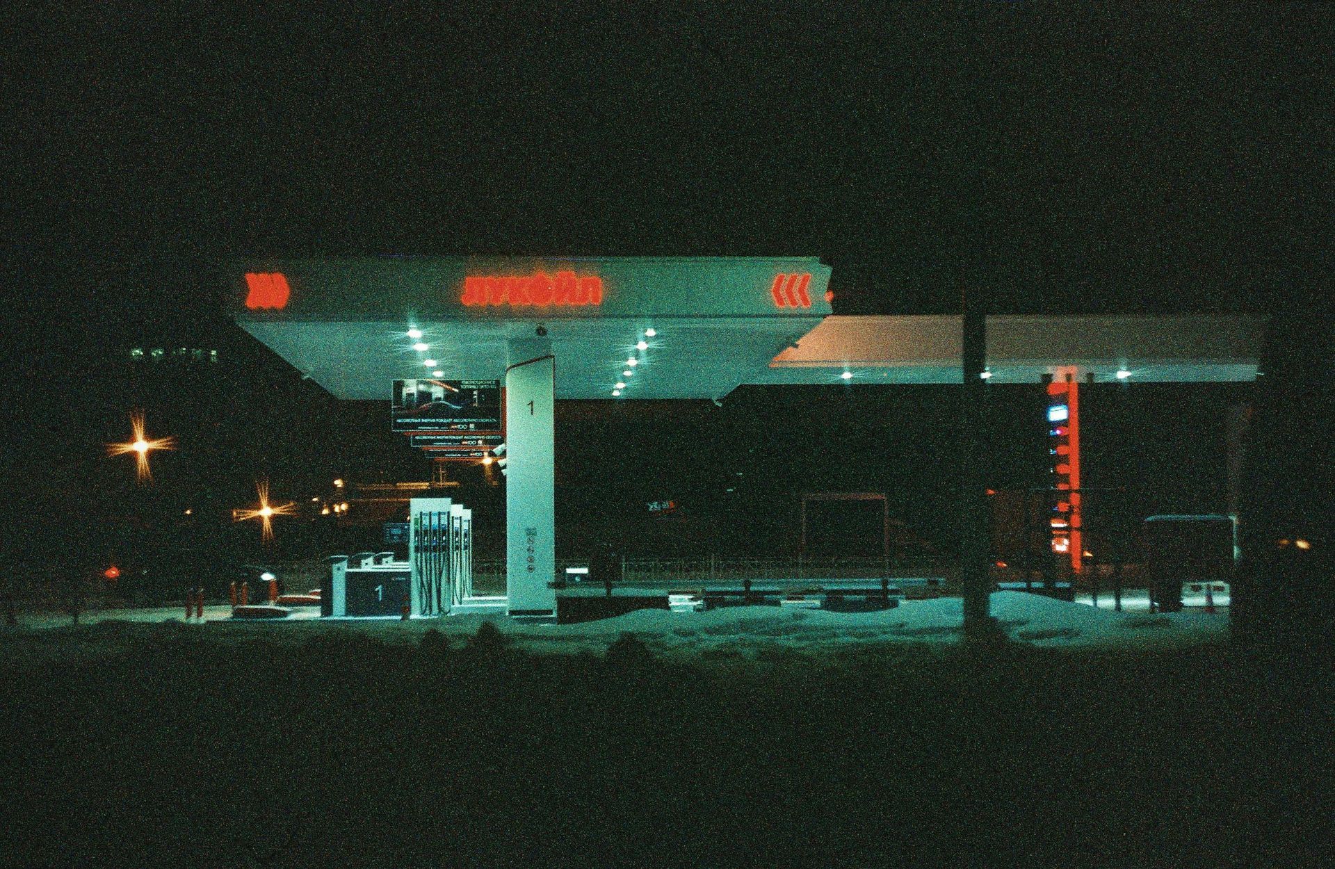 A gas station is lit up at night with red lights.